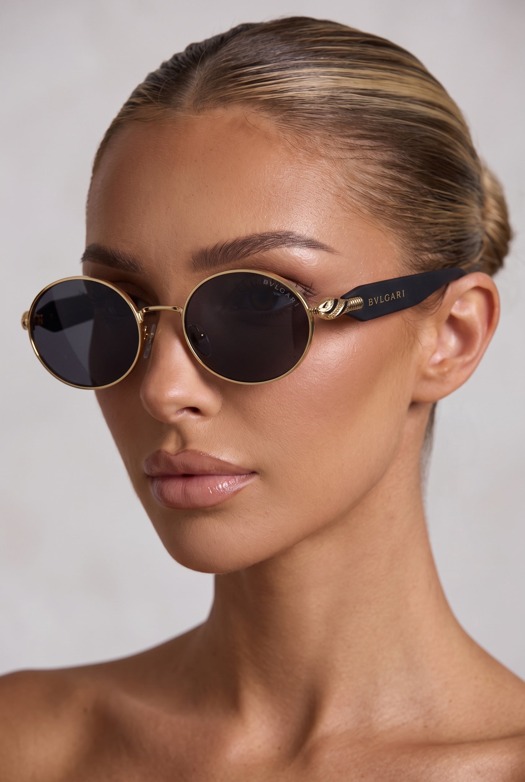 Bvlgari round gold rim sunglasses with black temples on model