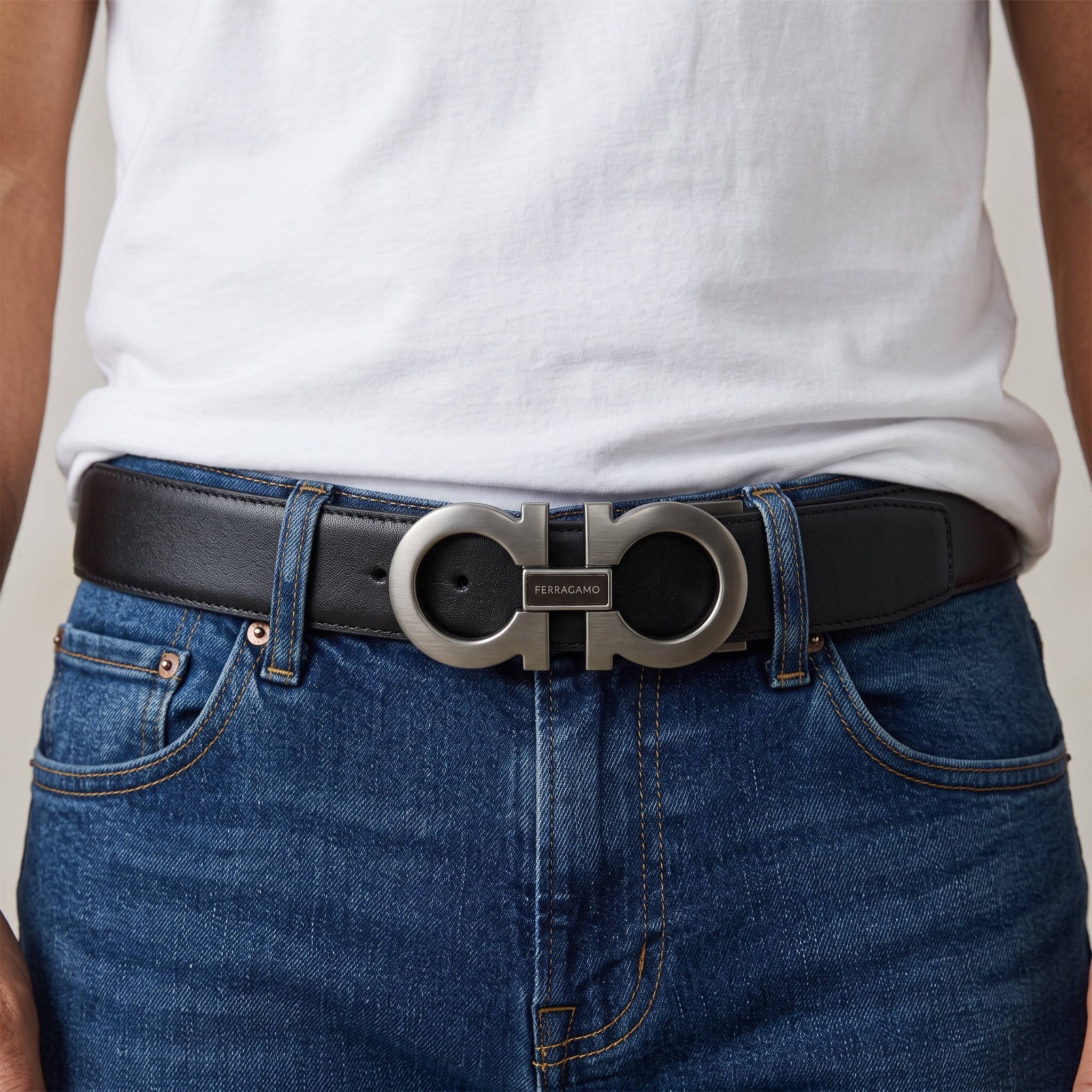 Ferragamo black leather belt with metal Gancini buckle shown on jeans