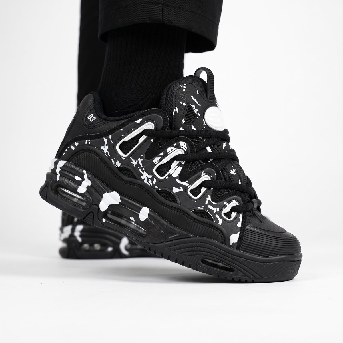 black chunky low-top sneaker with white splatter print and sculpted sole