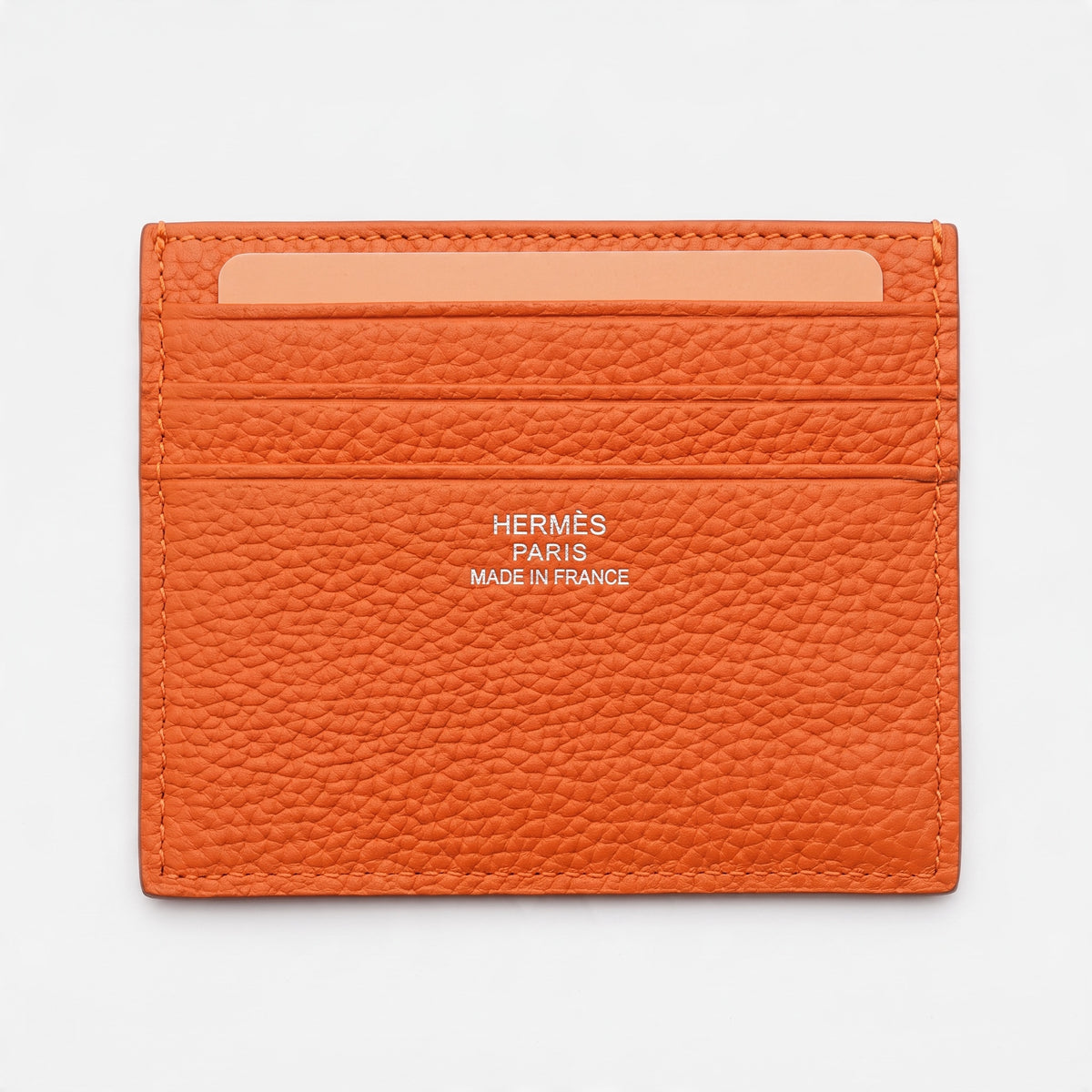 Orange Hermès pebbled leather card holder with embossed H and Hermès Paris stamp