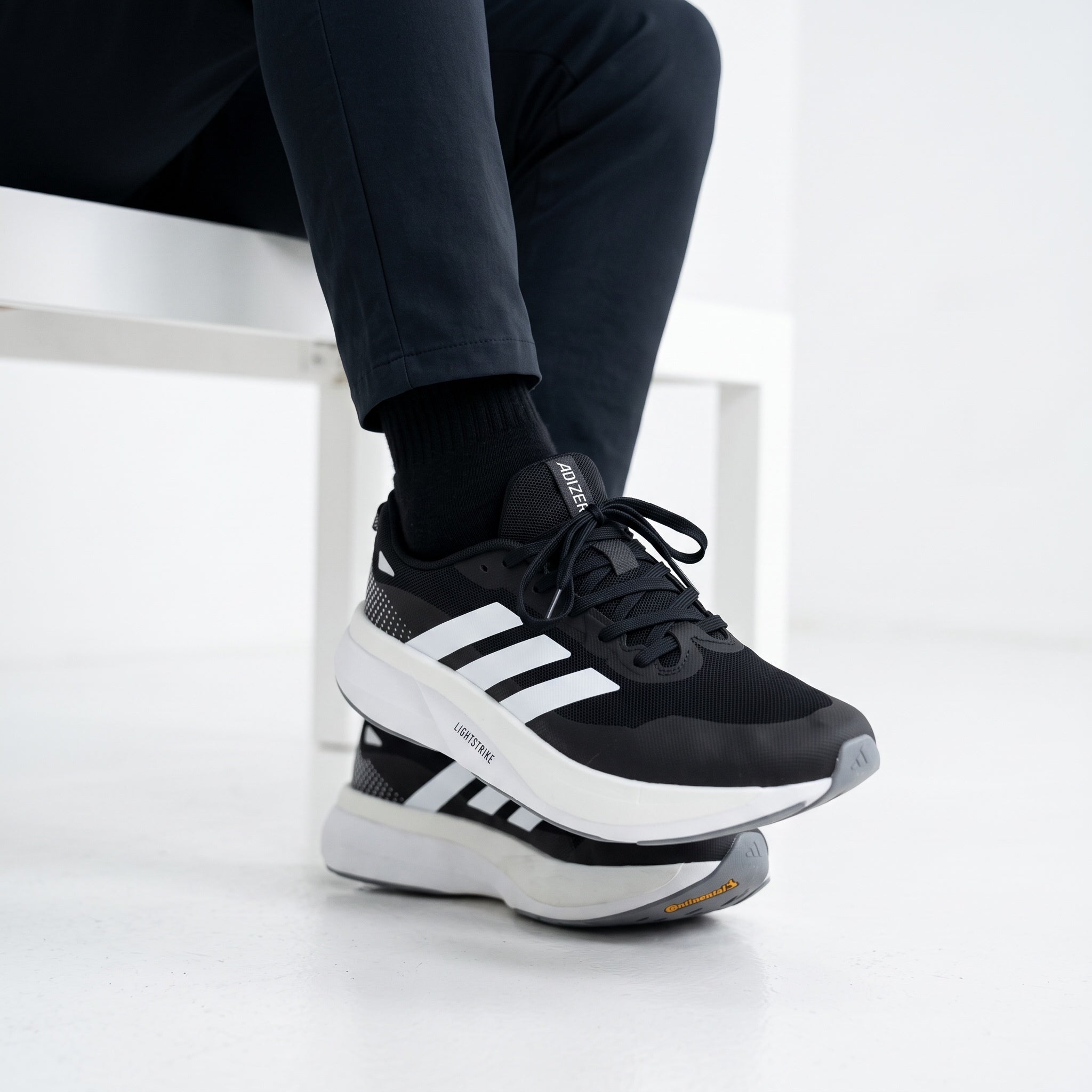 Black Adidas Adizero running sneaker with white midsole and three stripes