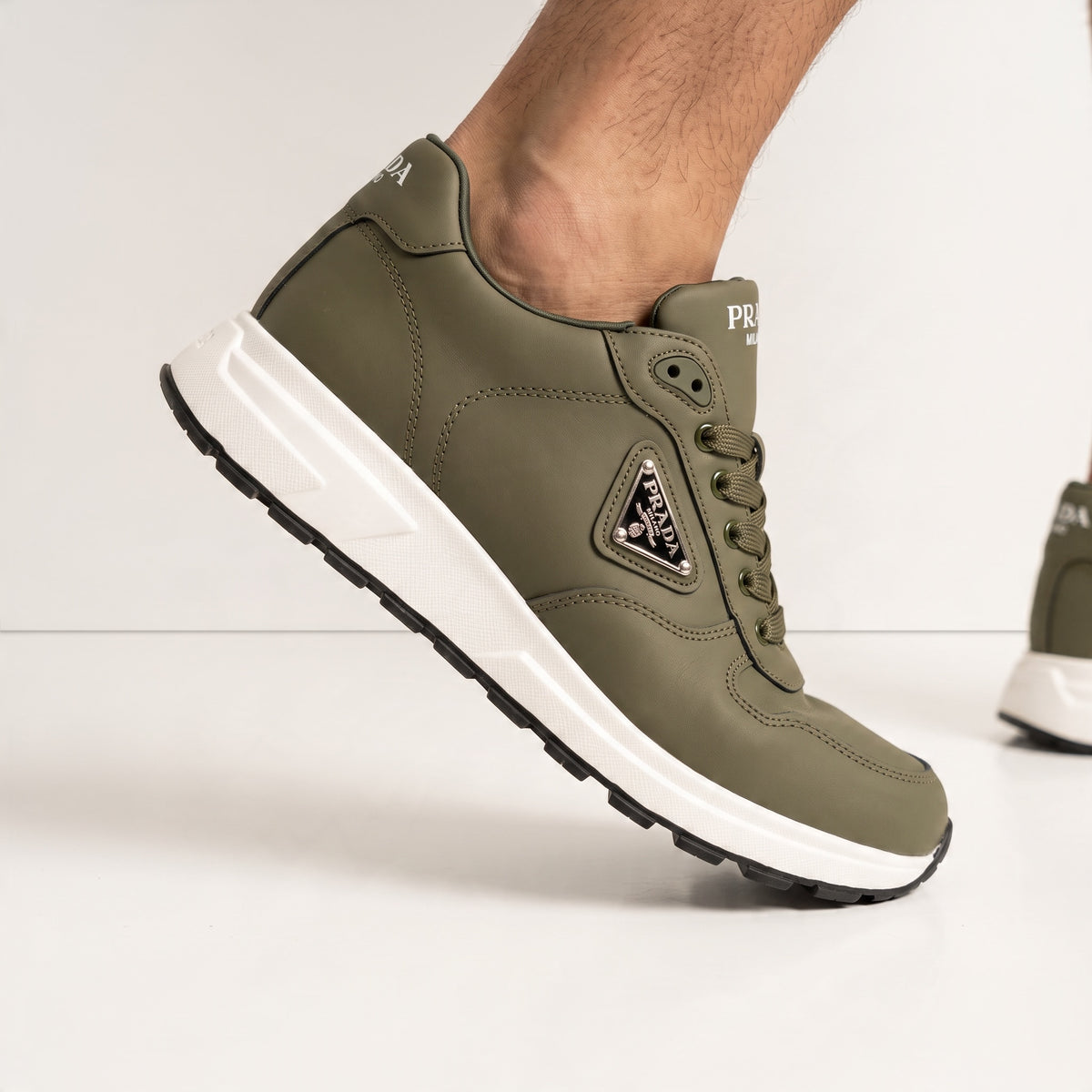 Olive green Prada low-top trainer with white chunky sole and triangular logo plaque