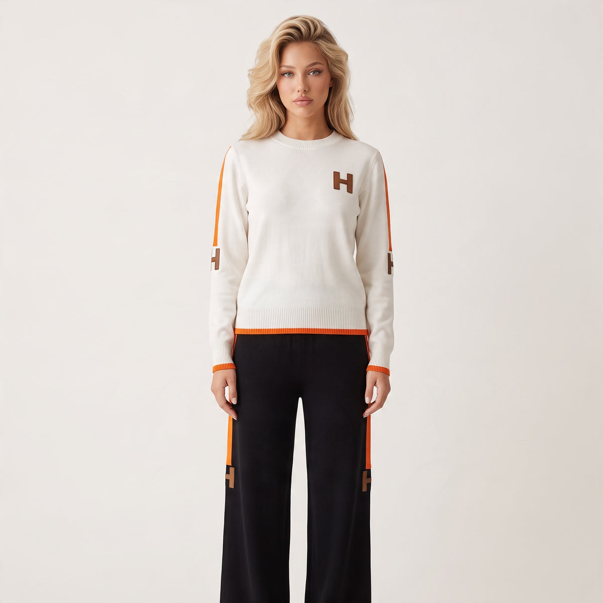 Ivory crewneck sweater with orange trim and brown H logos on chest and sleeves