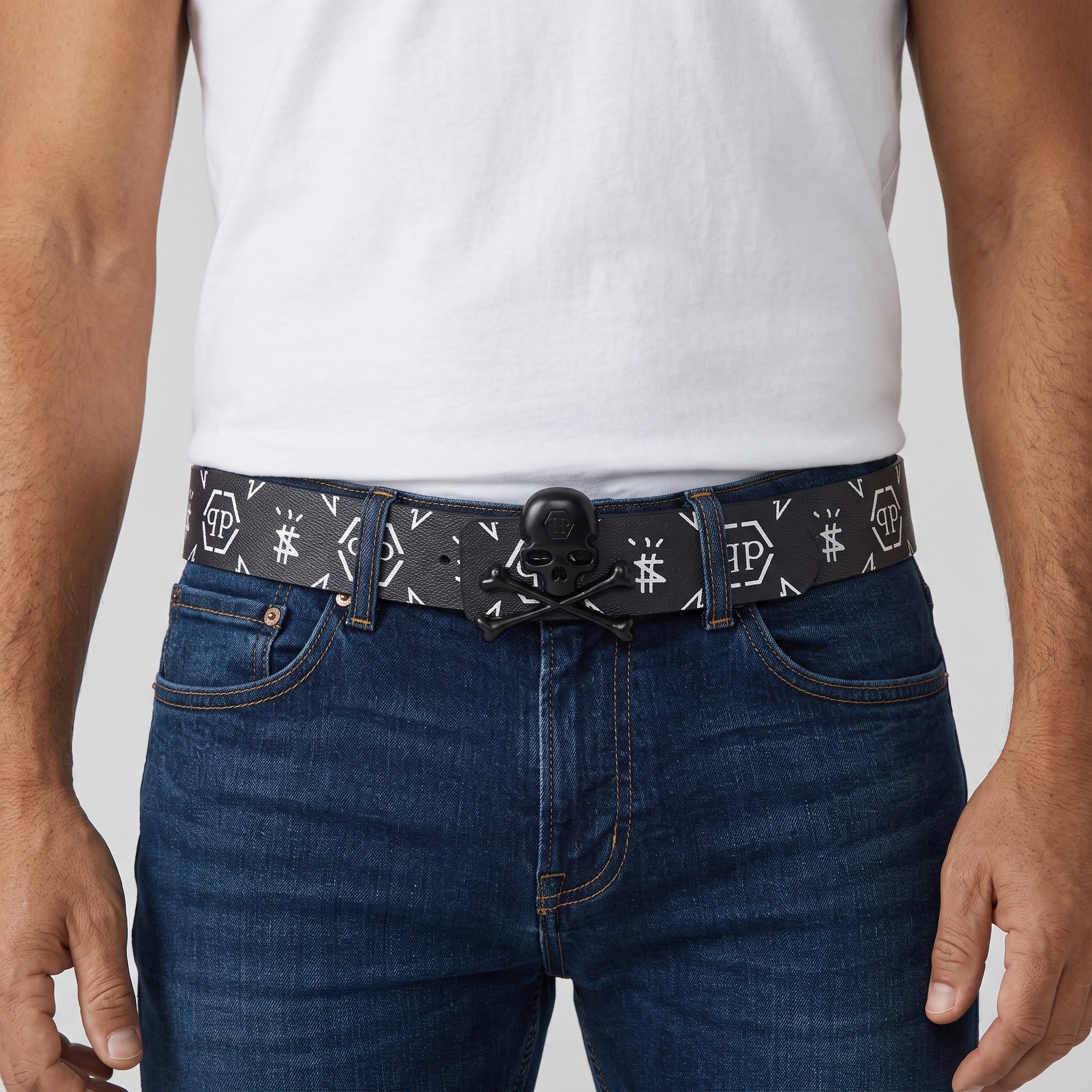Black belt with white monogram print and matte black skull buckle worn with jeans