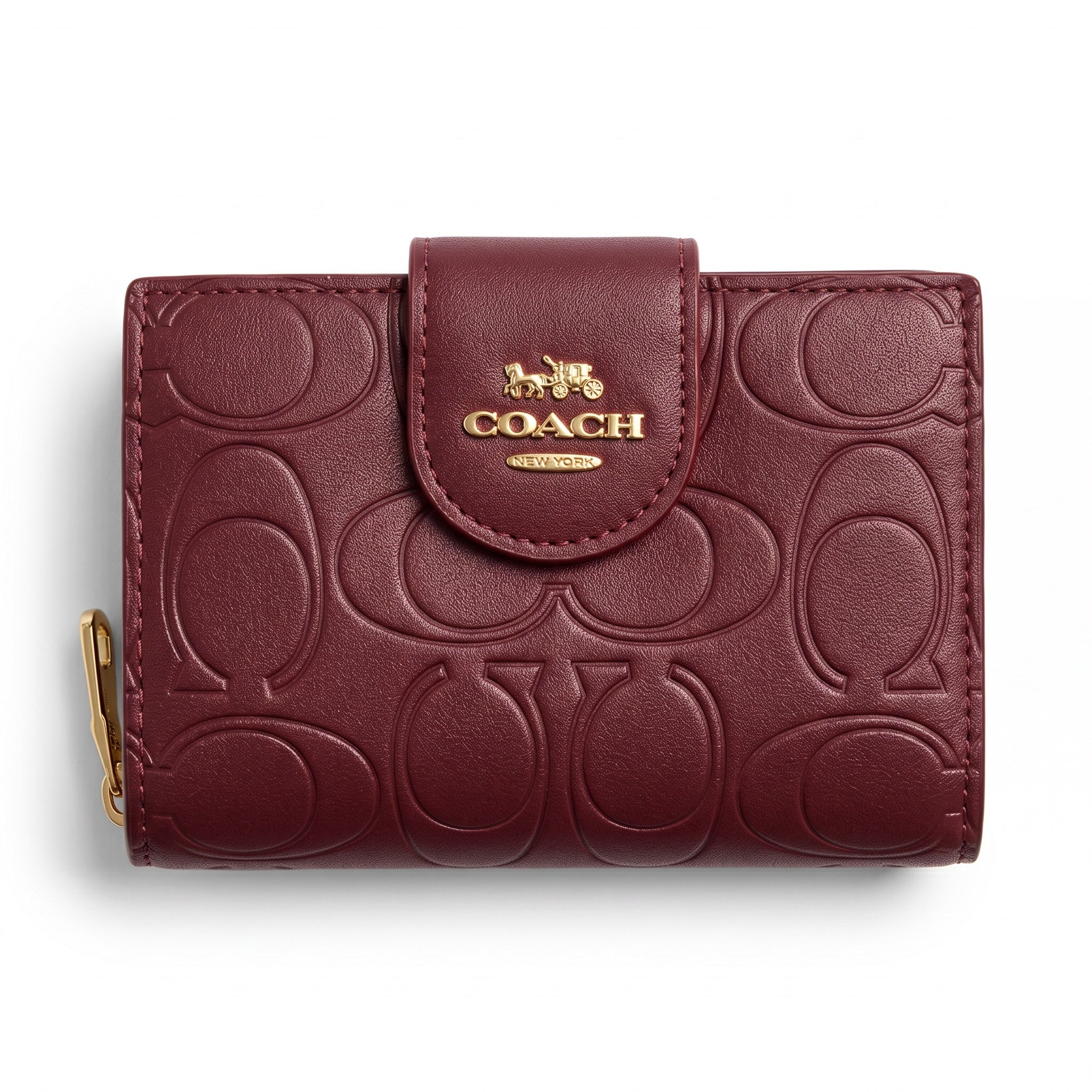Burgundy Coach compact wallet with embossed signature pattern and gold logo