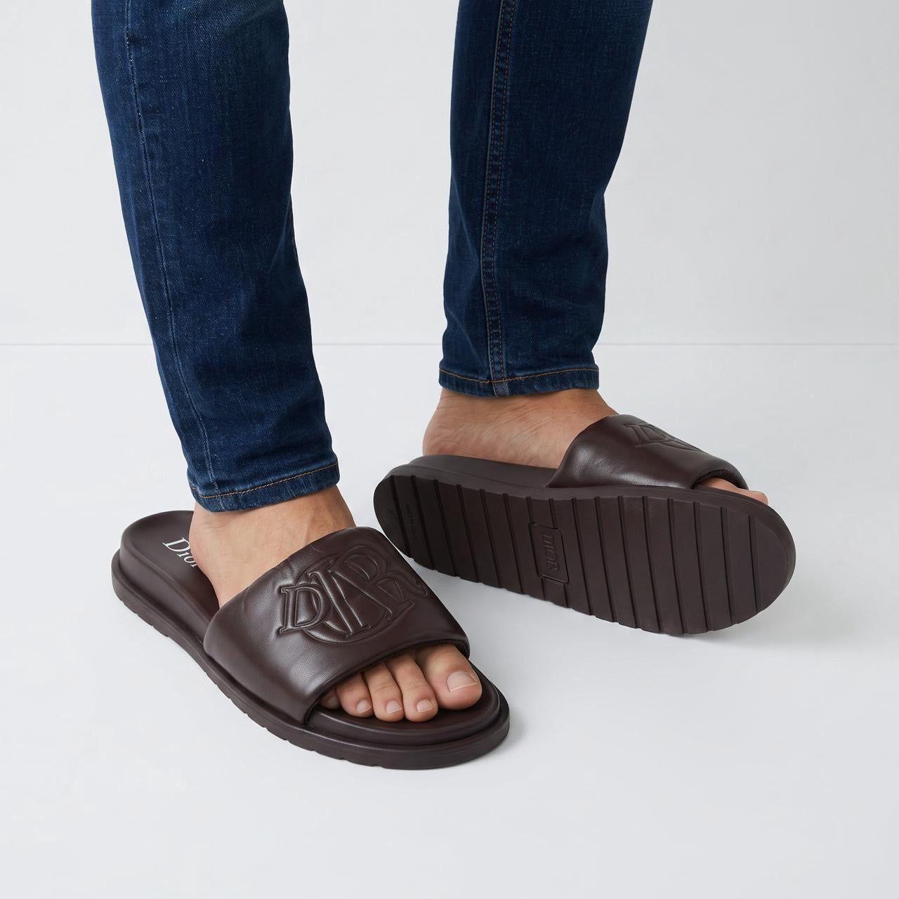 Dior dark brown padded slide sandals with embossed monogram on foot