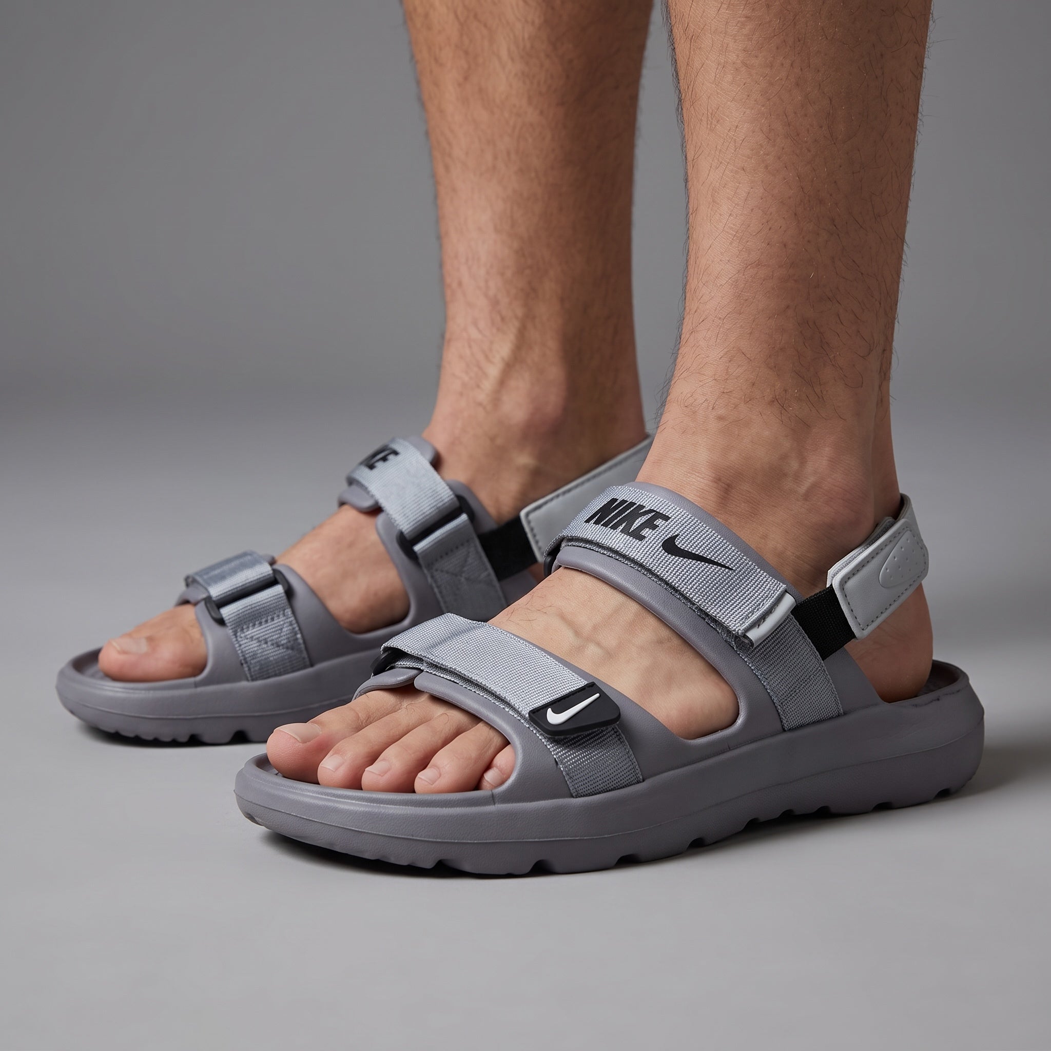 Grey Nike strappy sport sandals with adjustable webbing straps on model feet