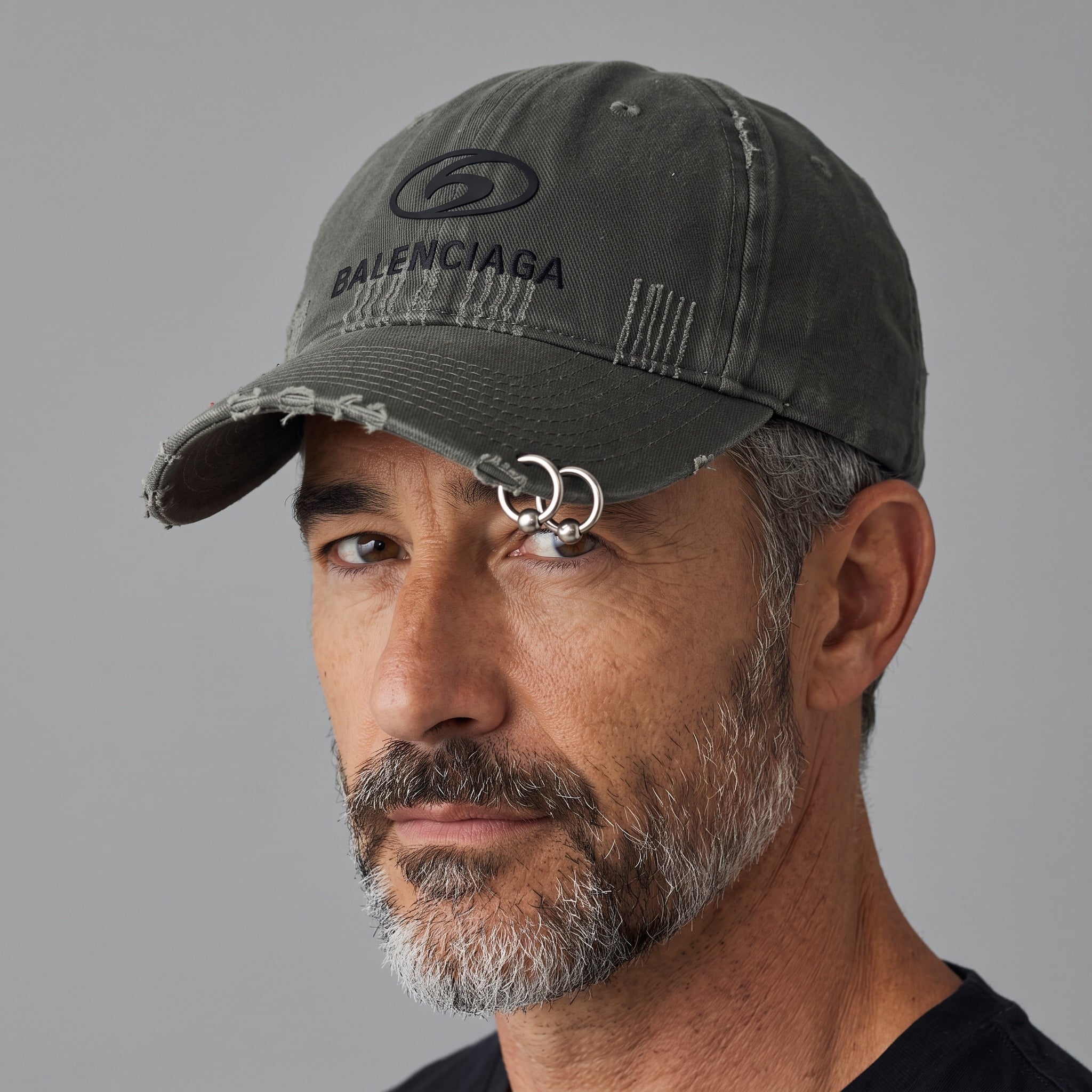Black distressed baseball cap with silver ring piercing detail on the brim and embroidered logo