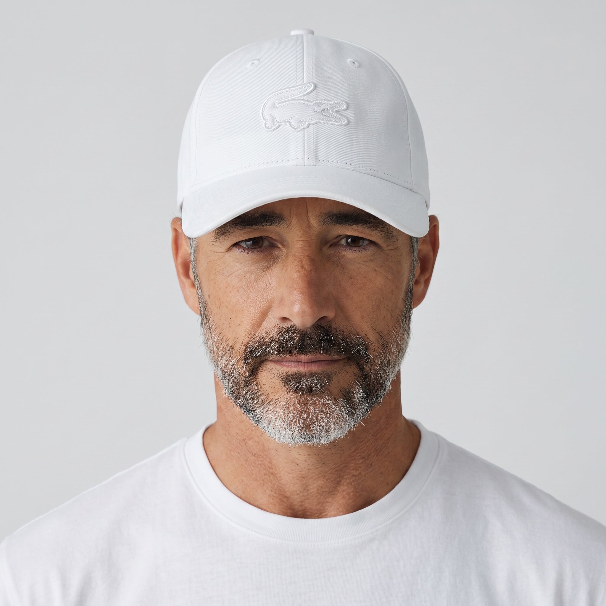 Man wearing a white Lacoste baseball cap with embroidered croc logo