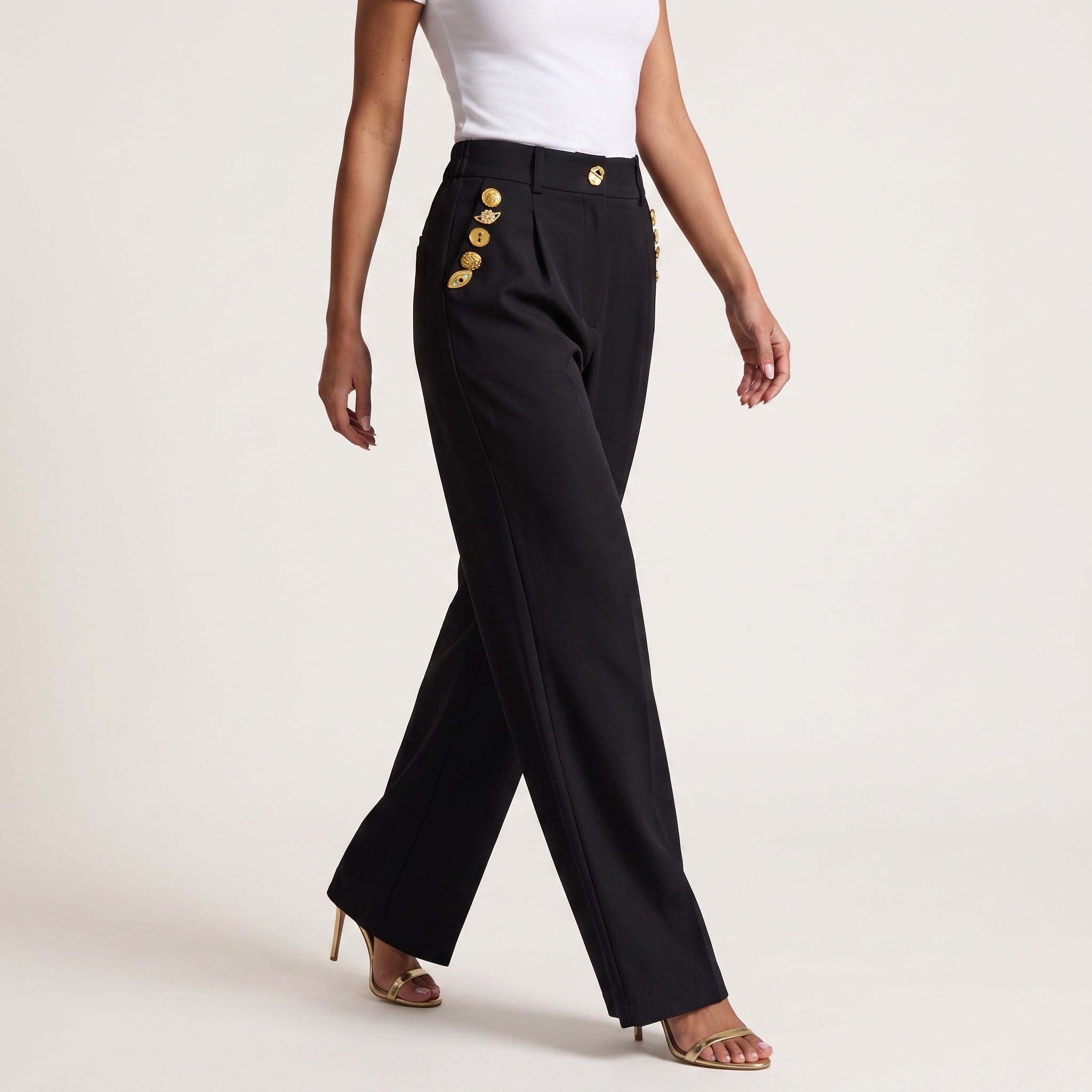 High-waist black trousers with gold decorative buttons down the sides and waist