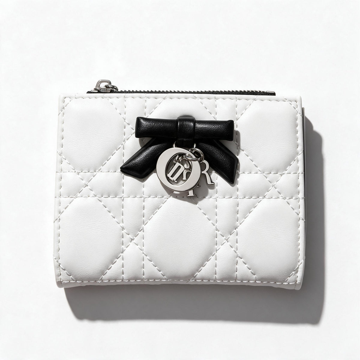 White quilted Dior compact wallet with black bow charm and black interior card slots