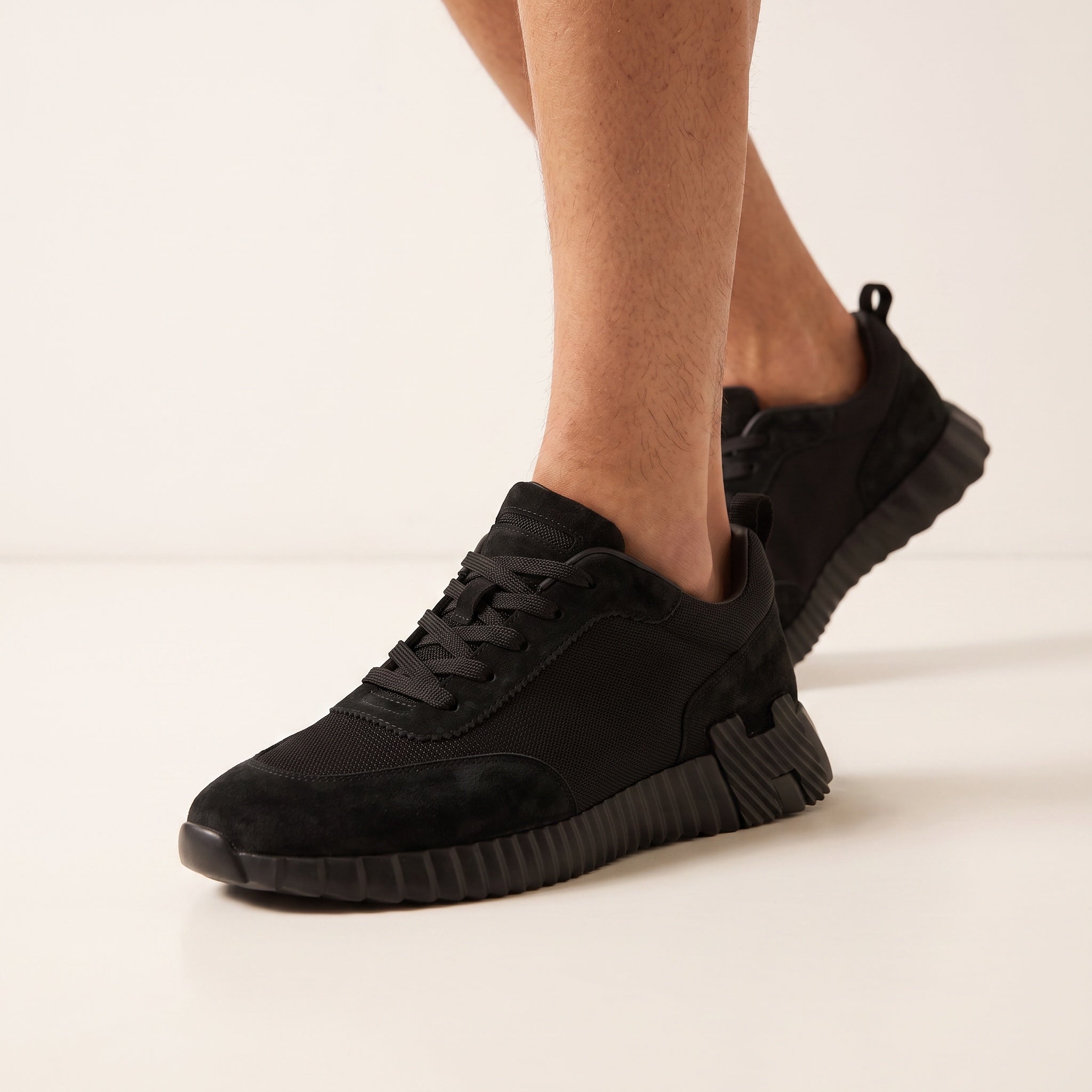 all‑black low top sneaker with ridged chunky sole and pull tab