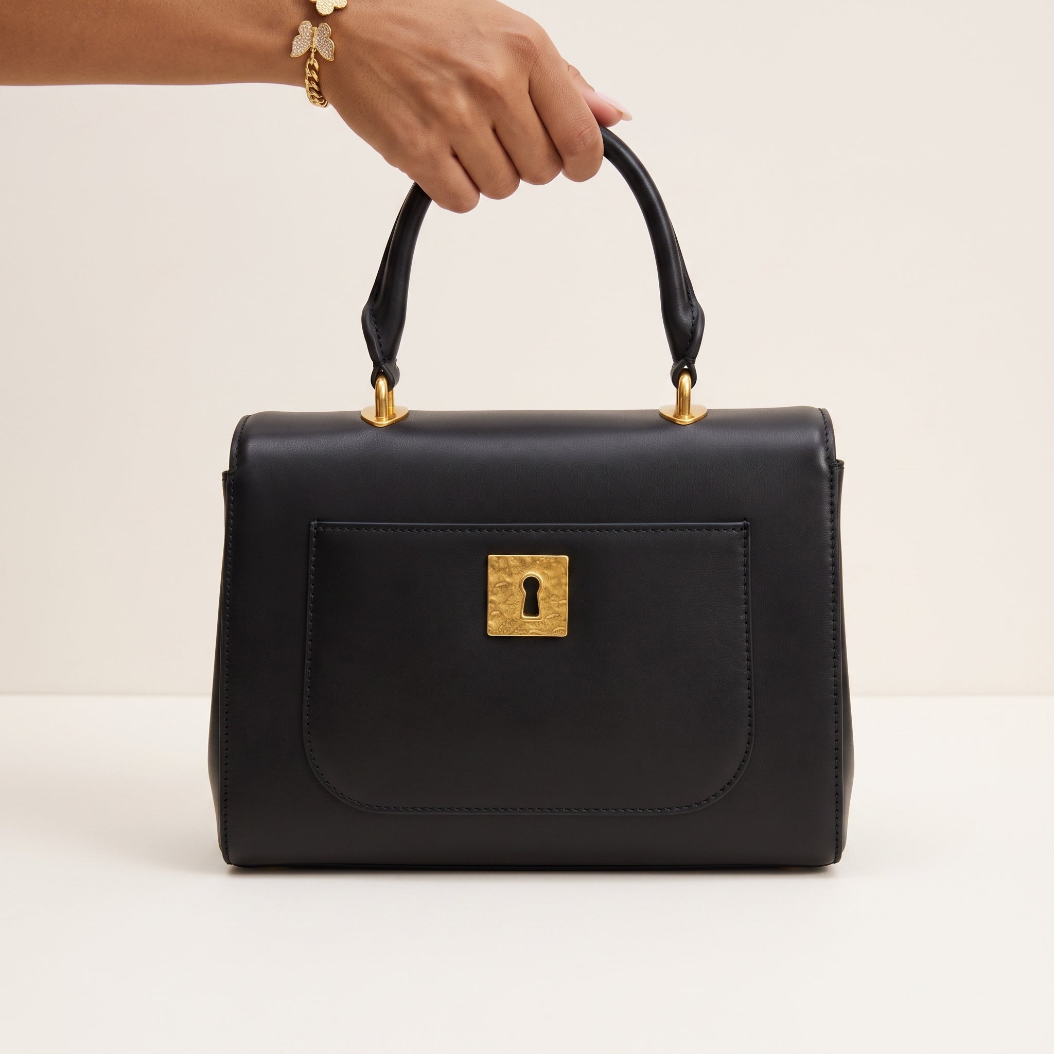 black top-handle bag with gold decorative hardware and front lock