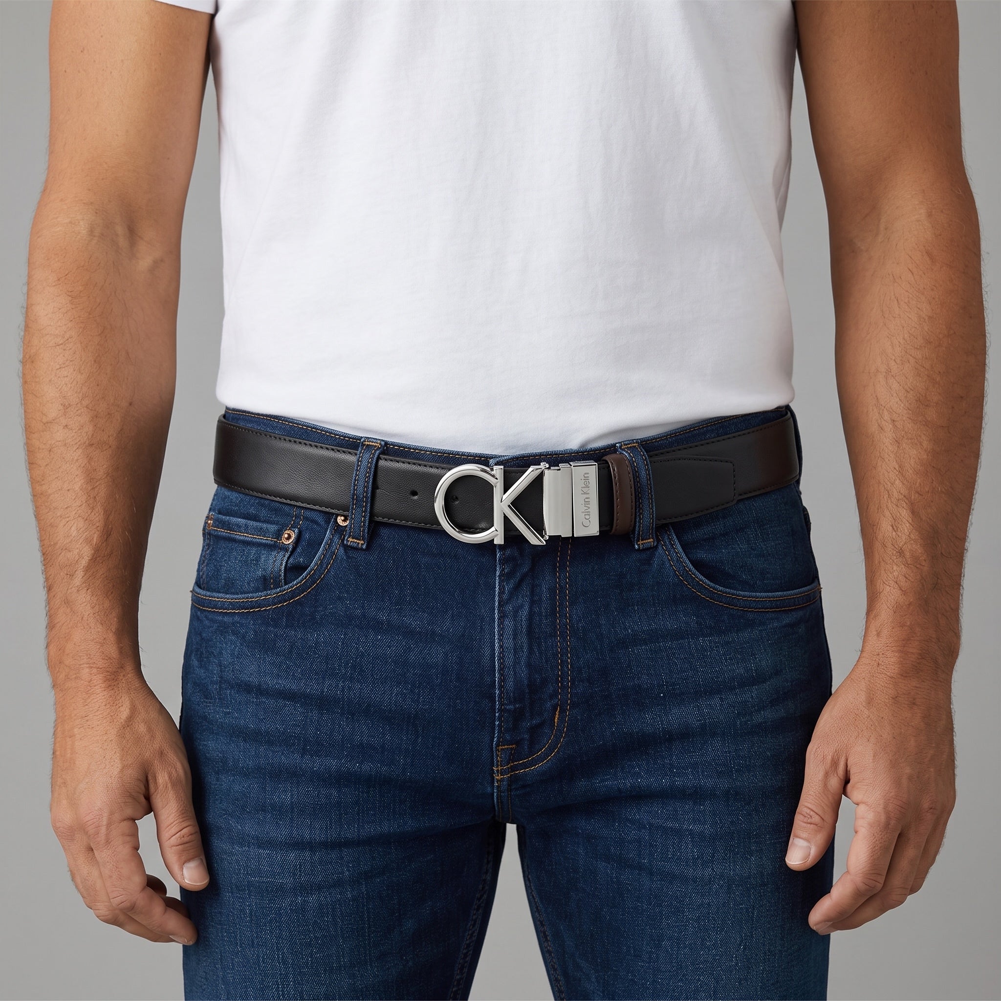 Black Calvin Klein belt with silver CK logo buckle on model wearing jeans