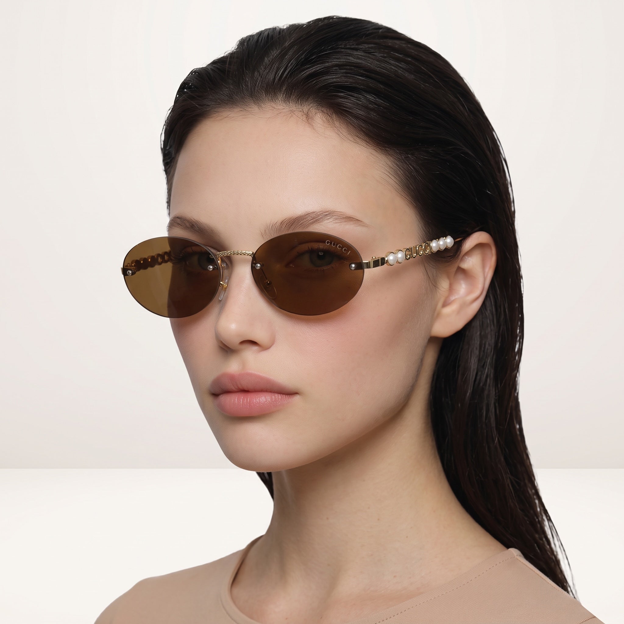 Gucci gold sunglasses with brown lenses and pearl-accented temples on model