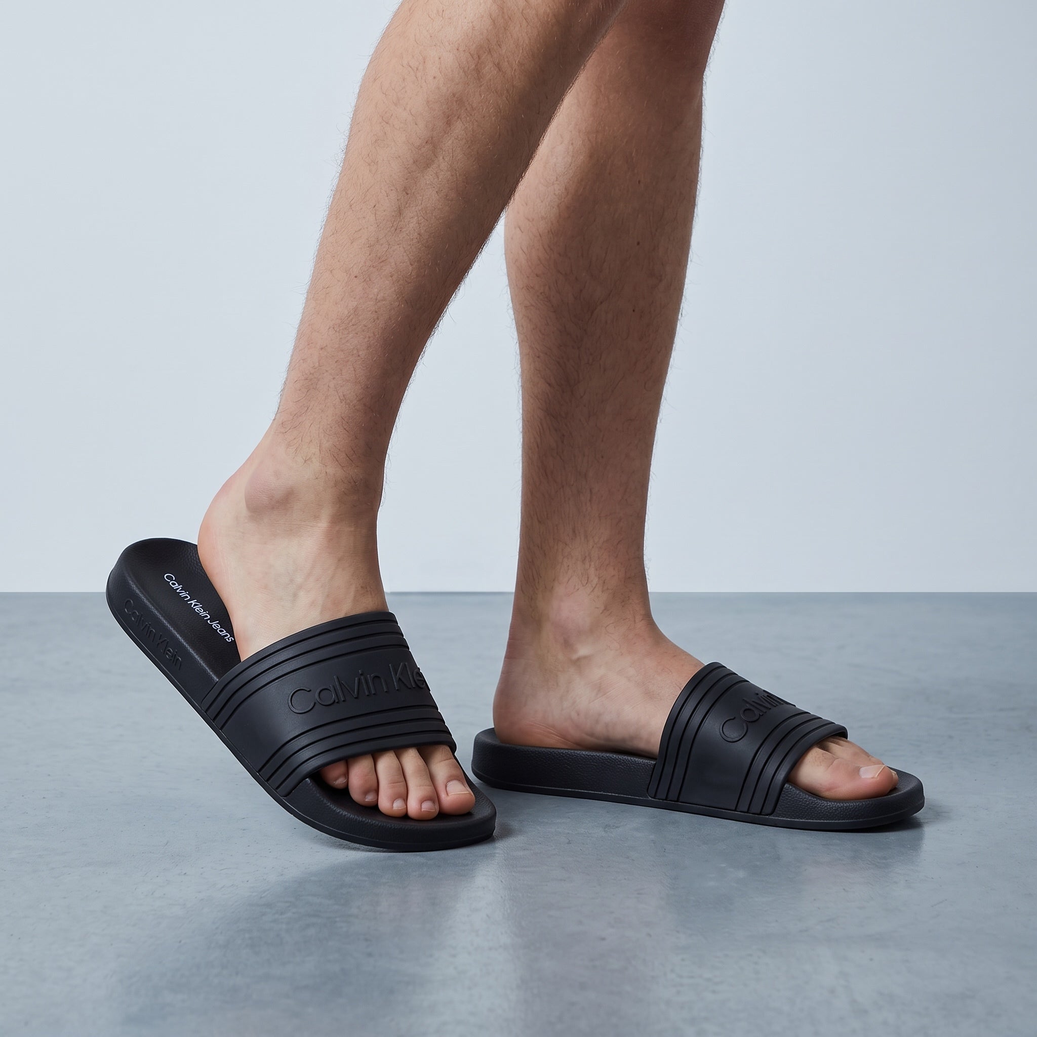 black Calvin Klein logo slides on male feet