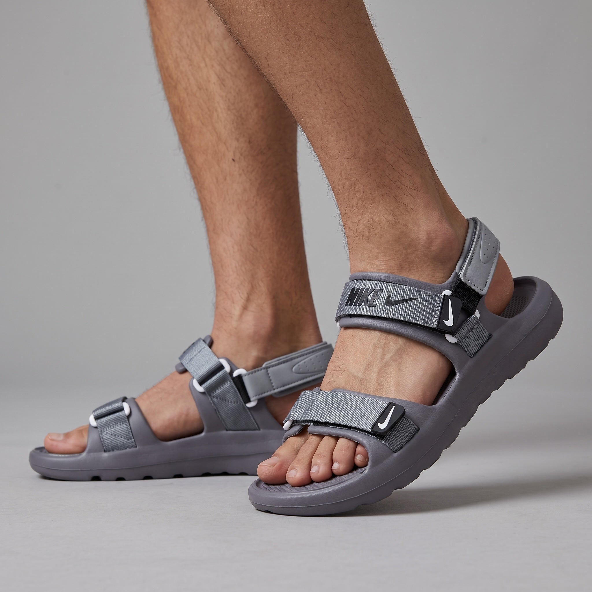 Grey Nike strappy sport sandals with adjustable webbing straps on model feet