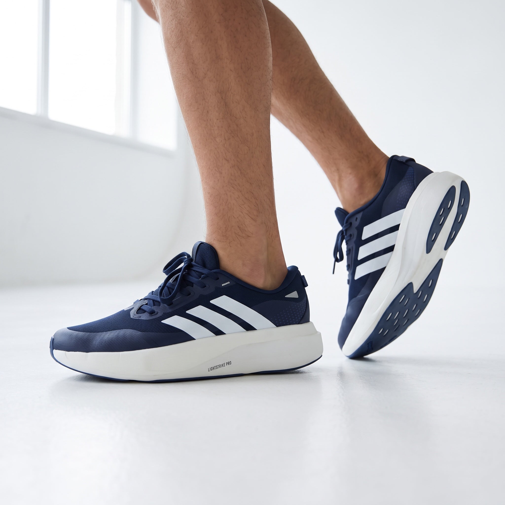 Navy and white Adidas sneakers shown on a model with chunky white sole