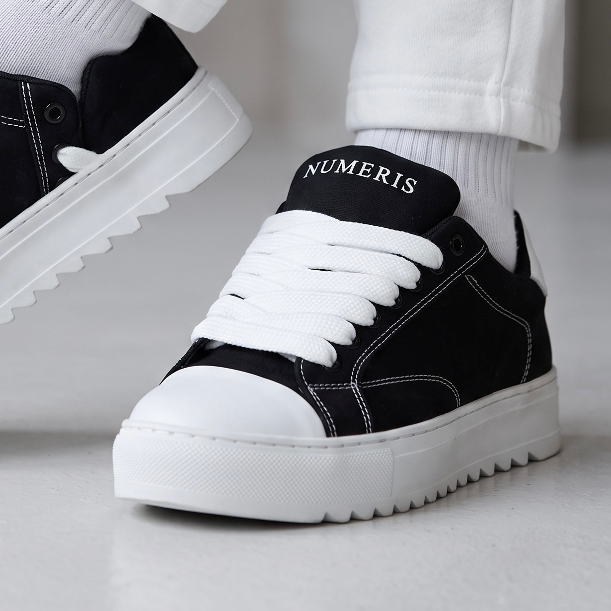 Black Numeris low-top sneakers with white laces, white toe cap and chunky ridged white sole