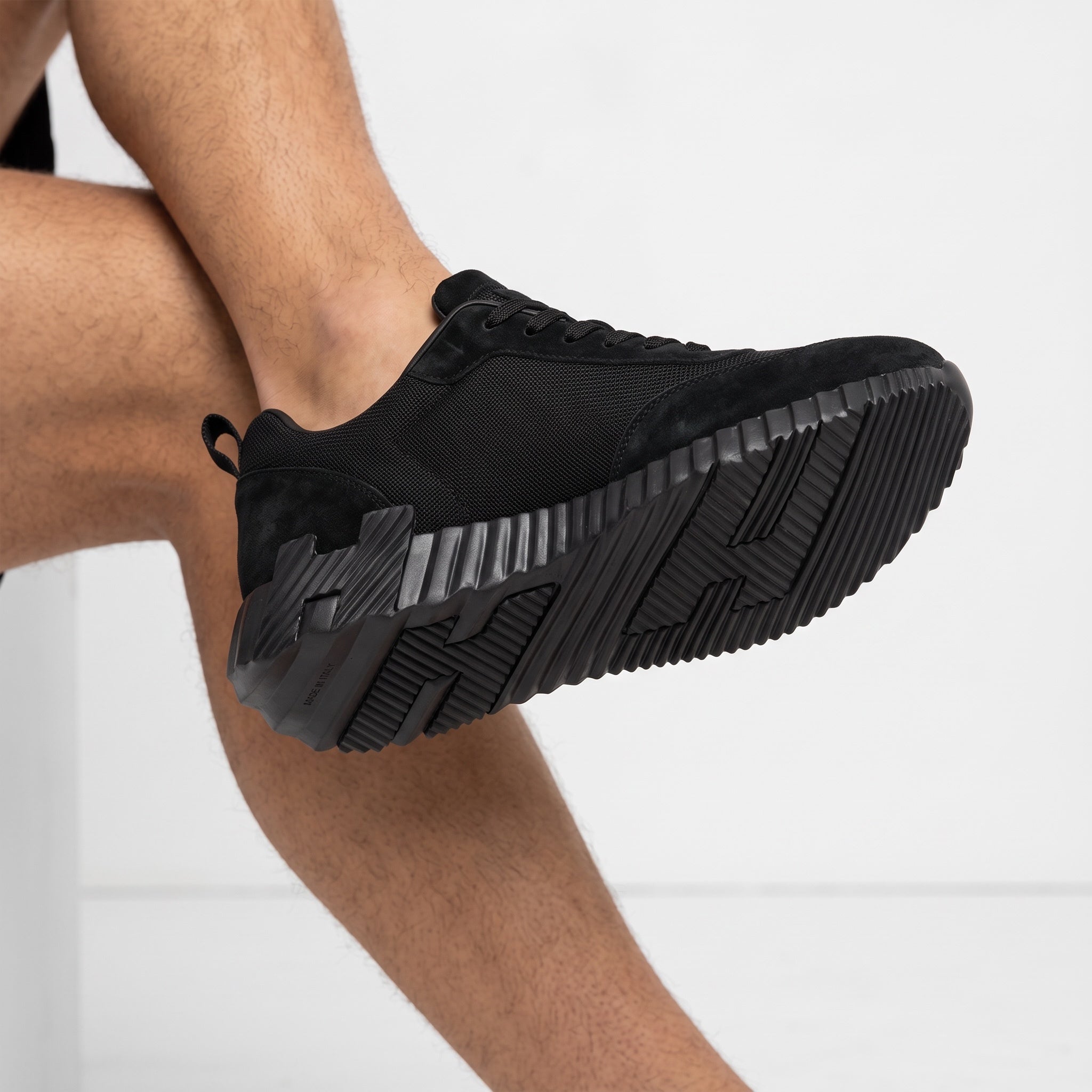 all‑black low top sneaker with ridged chunky sole and pull tab