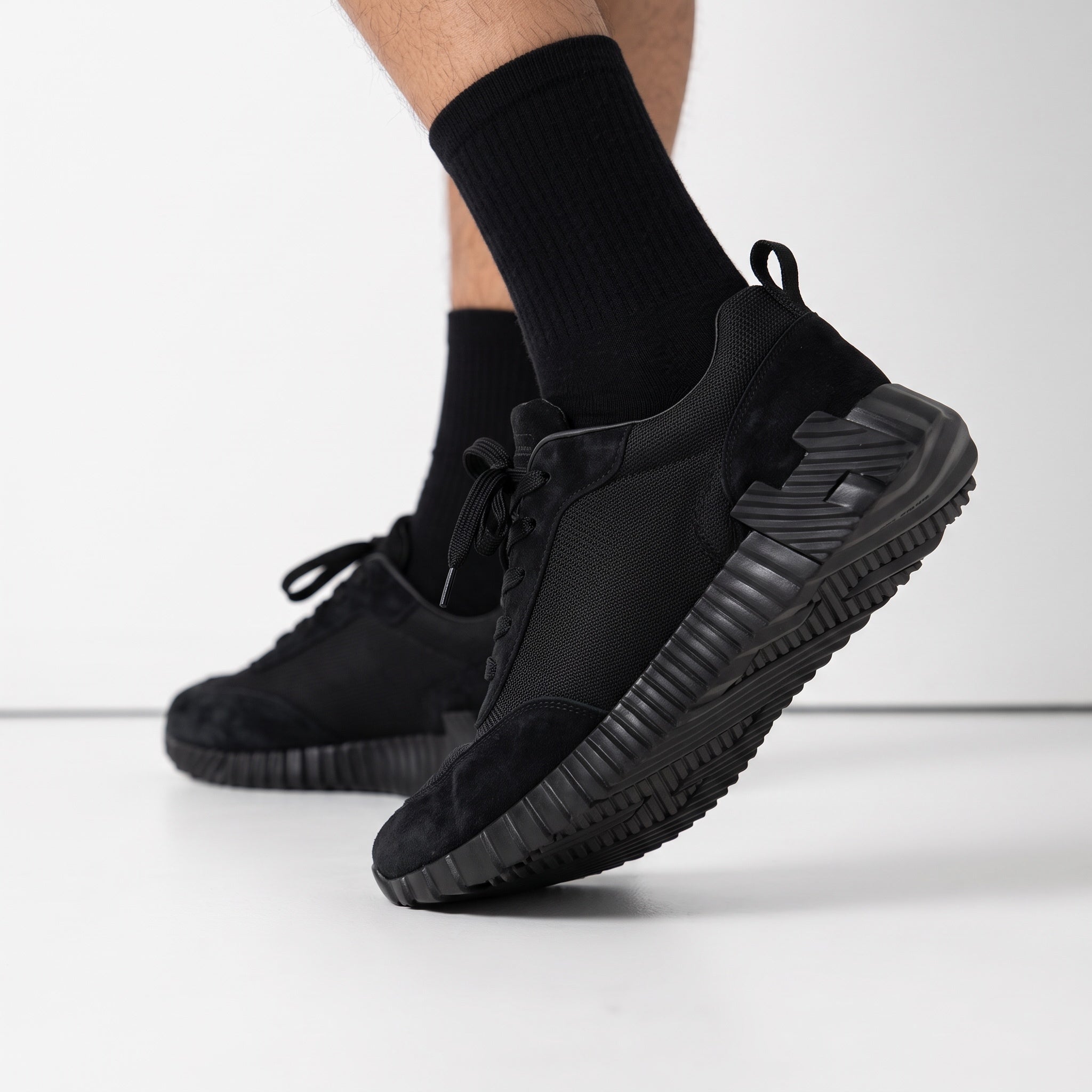 all‑black low top sneaker with ridged chunky sole and pull tab