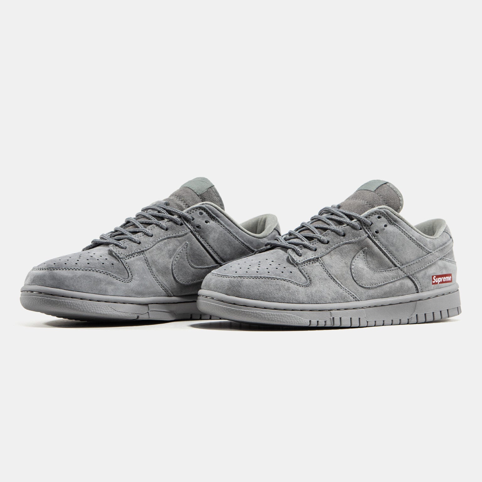 Grey Nike Dunk Low suede sneaker with small red Supreme box logo at heel