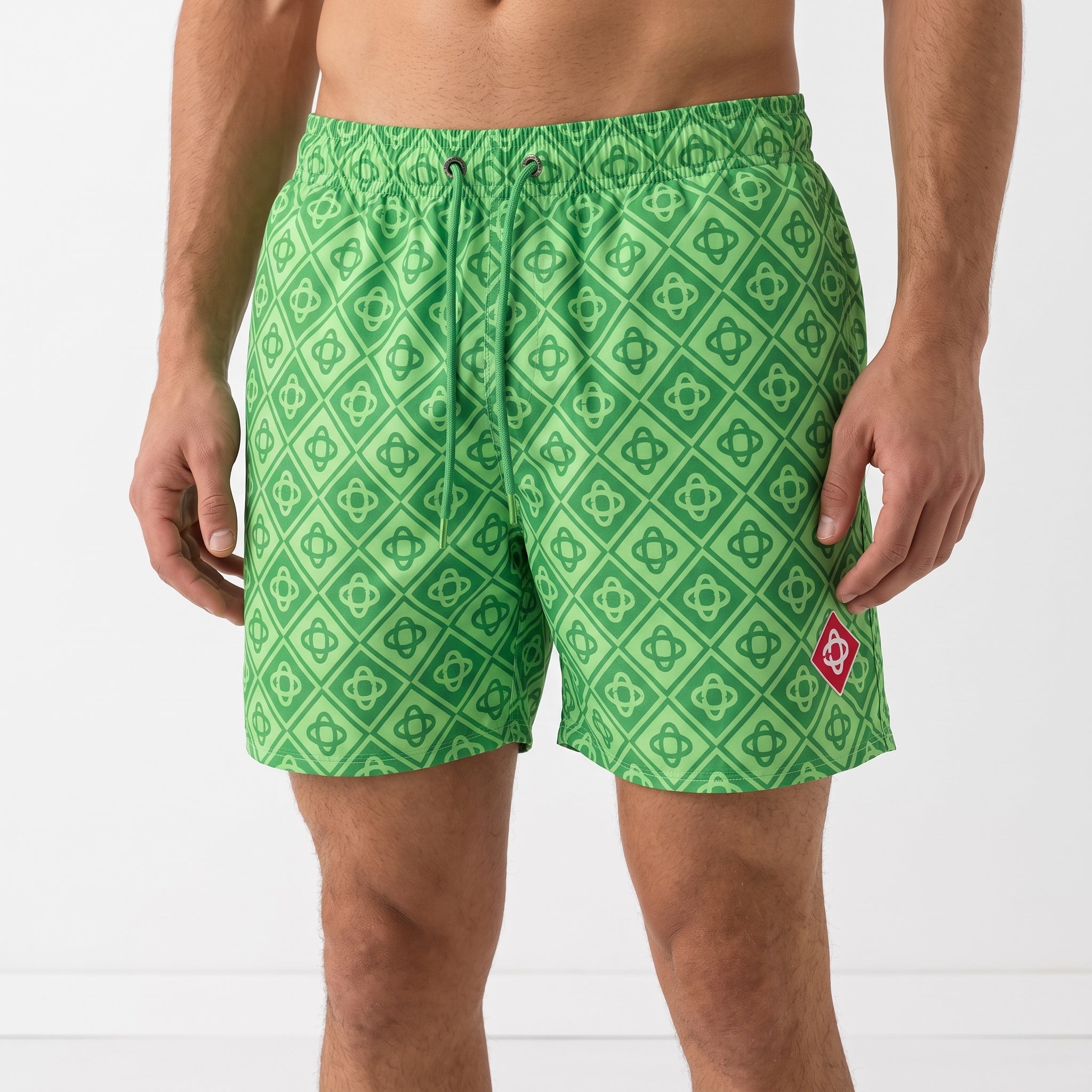 green geometric patterned men's swim shorts with drawstring and red badge on leg