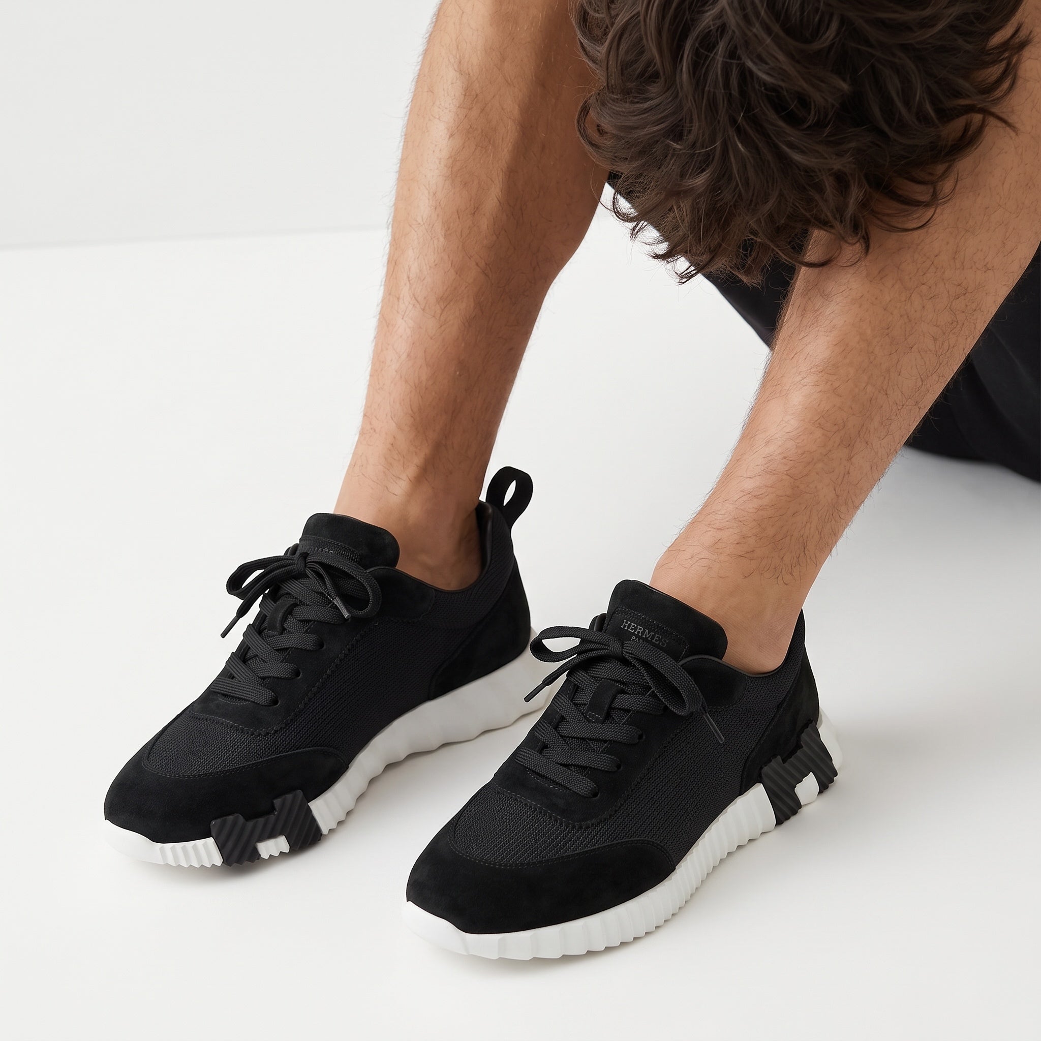 Hermès black low-top sneaker with white ridged sole and H-shaped black insert