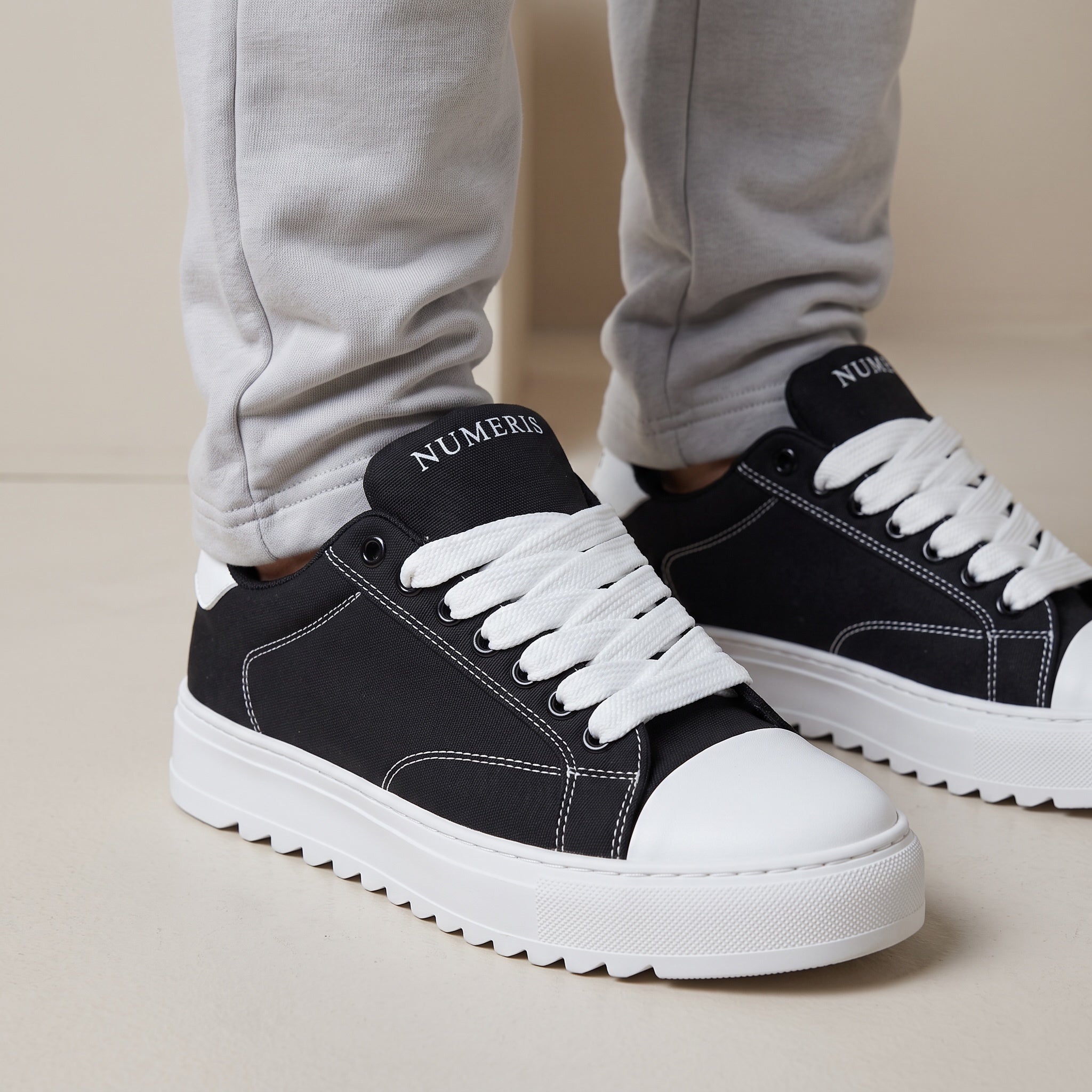 Black Numeris low-top sneakers with white laces, white toe cap and chunky ridged white sole