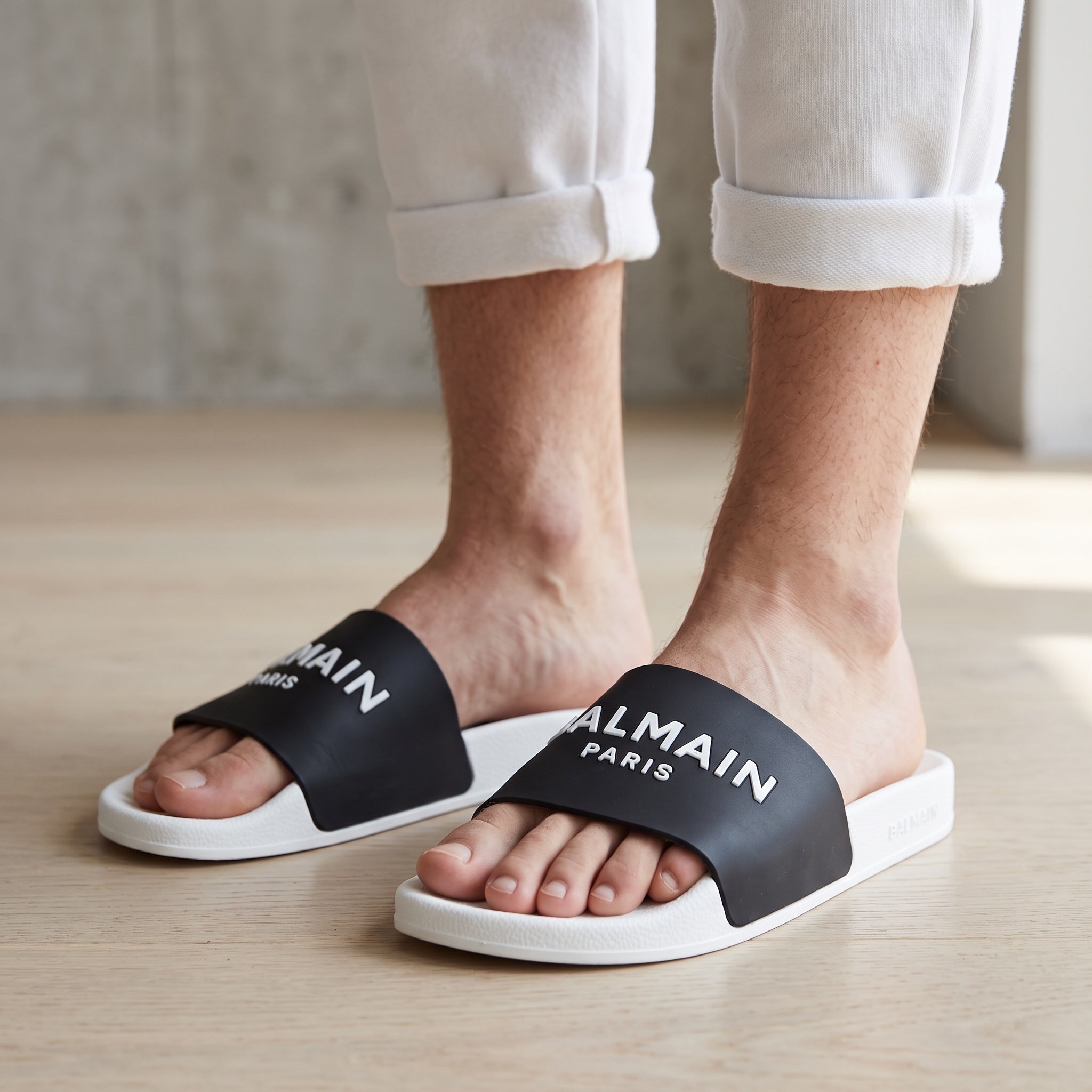 Black Balmain logo slide sandals with white sole seen on model feet