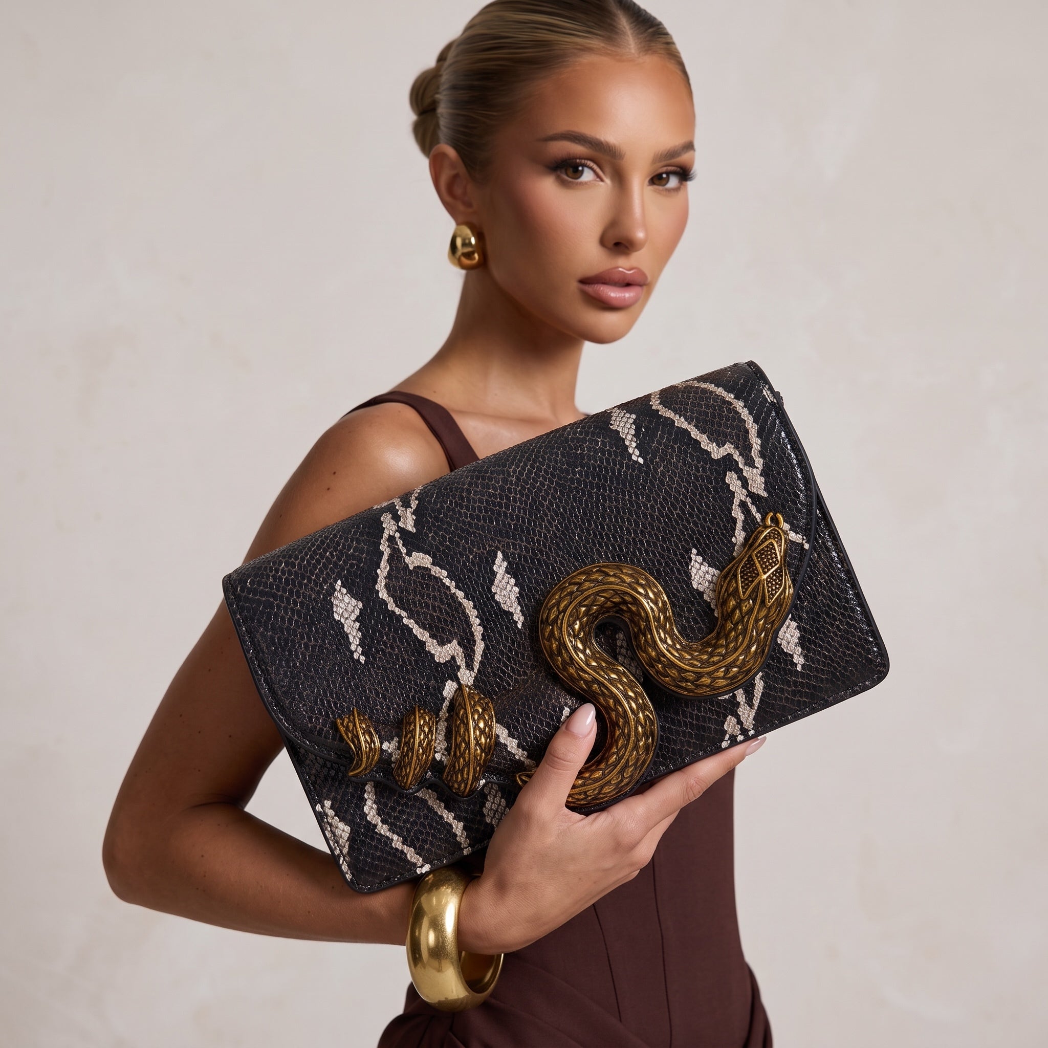 black snake-print clutch with gold snake hardware