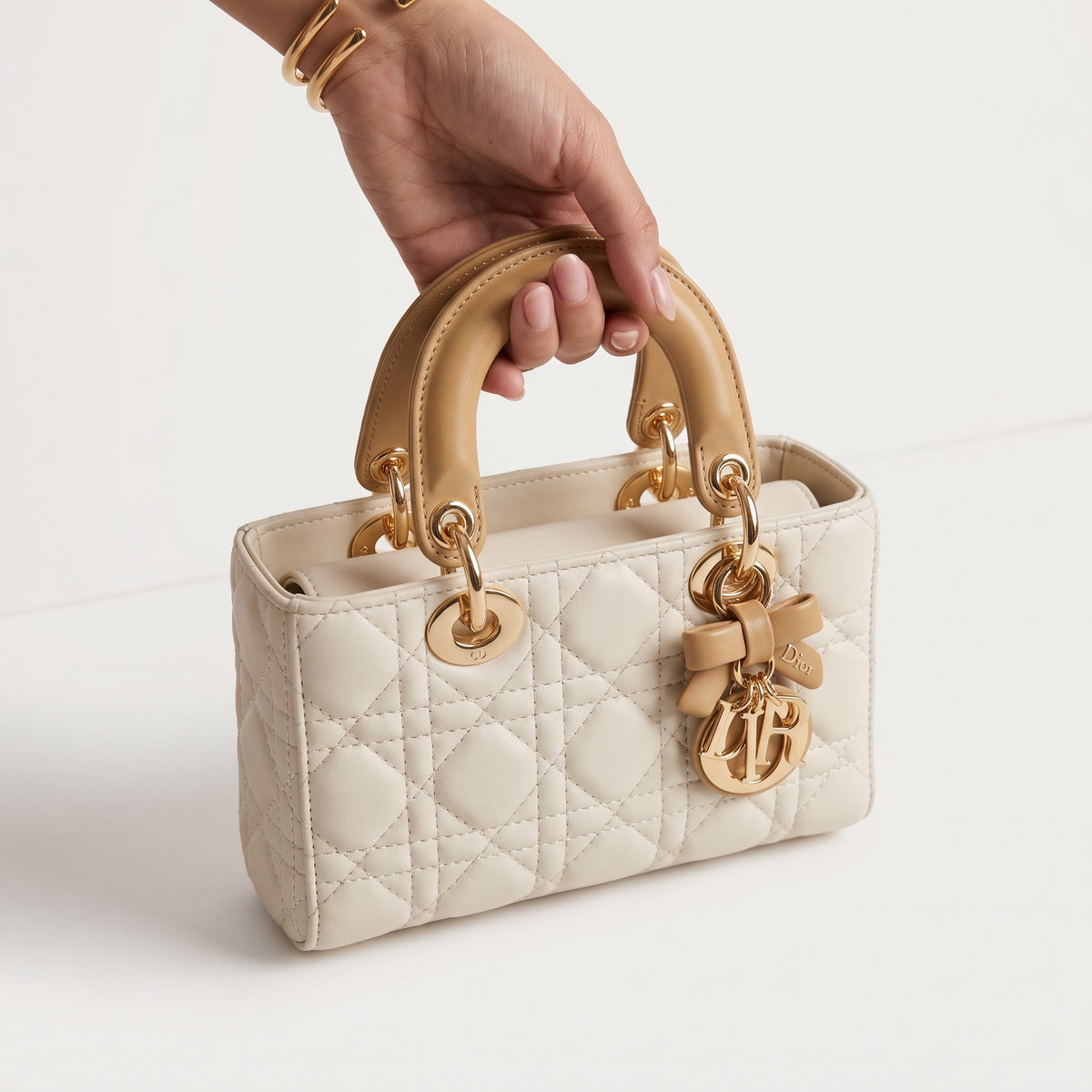 Cream Dior Lady Dior mini tote with beige handles and gold charms