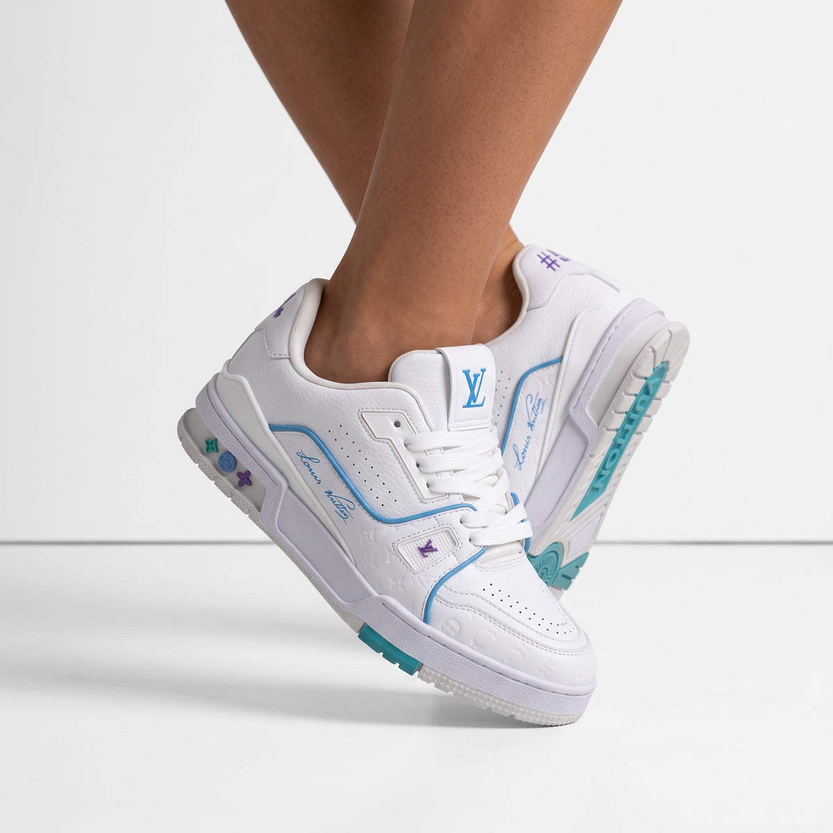 White Louis Vuitton low-top trainer with turquoise and purple accents, LV logo on tongue and embossed monogram