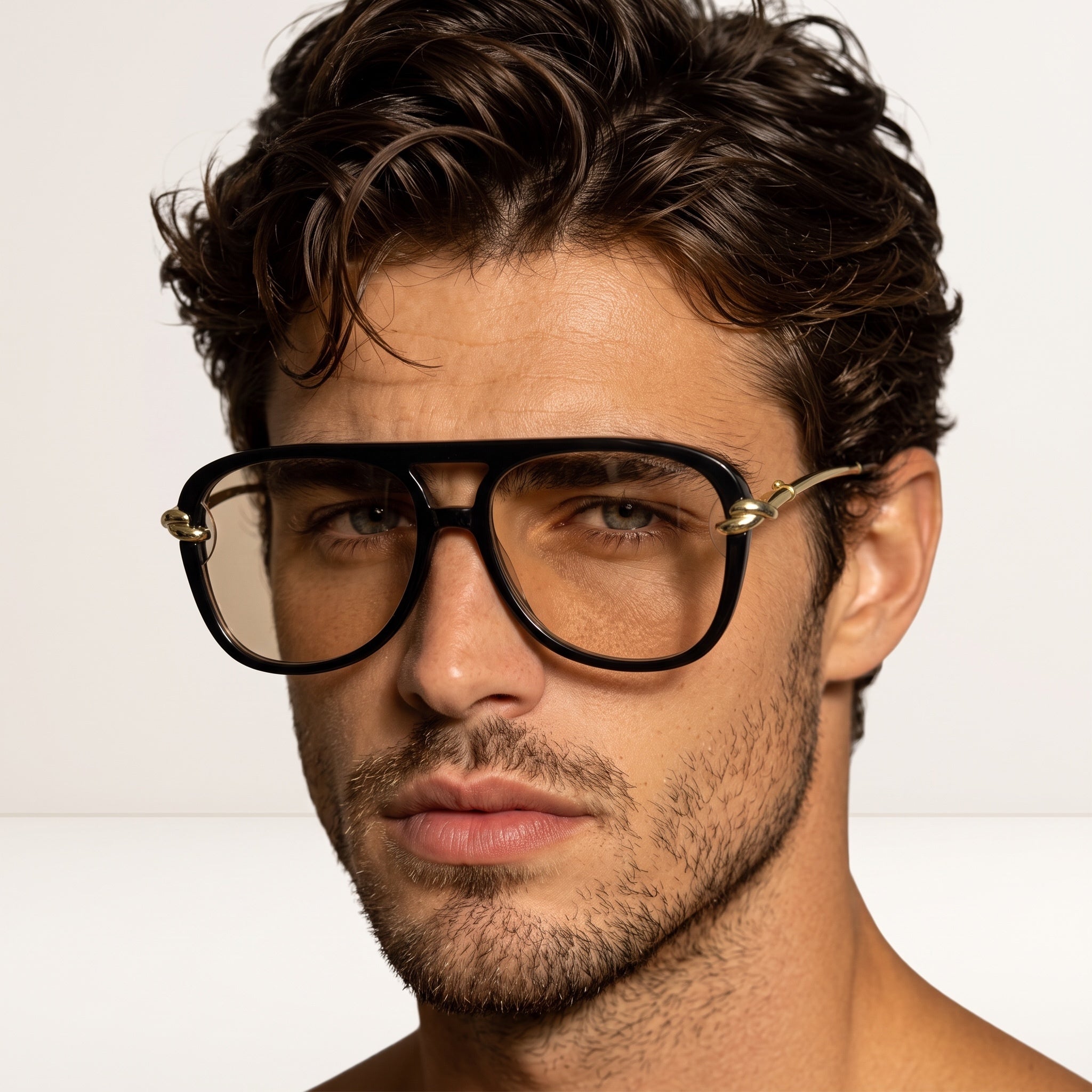 Close-up of oversized black aviator sunglasses with gold hardware and brown lenses on a male model