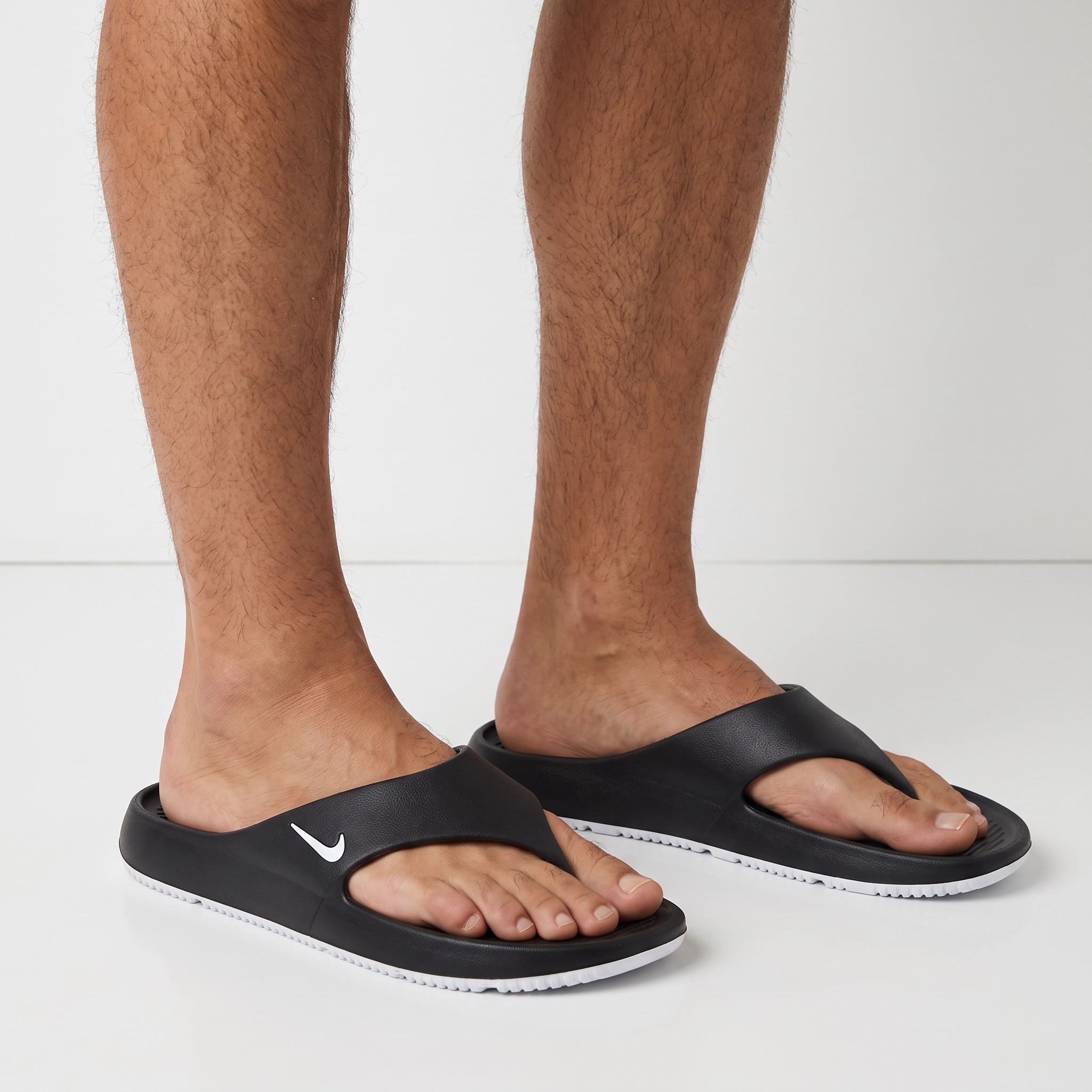 black Nike slides with white sole on a model's feet