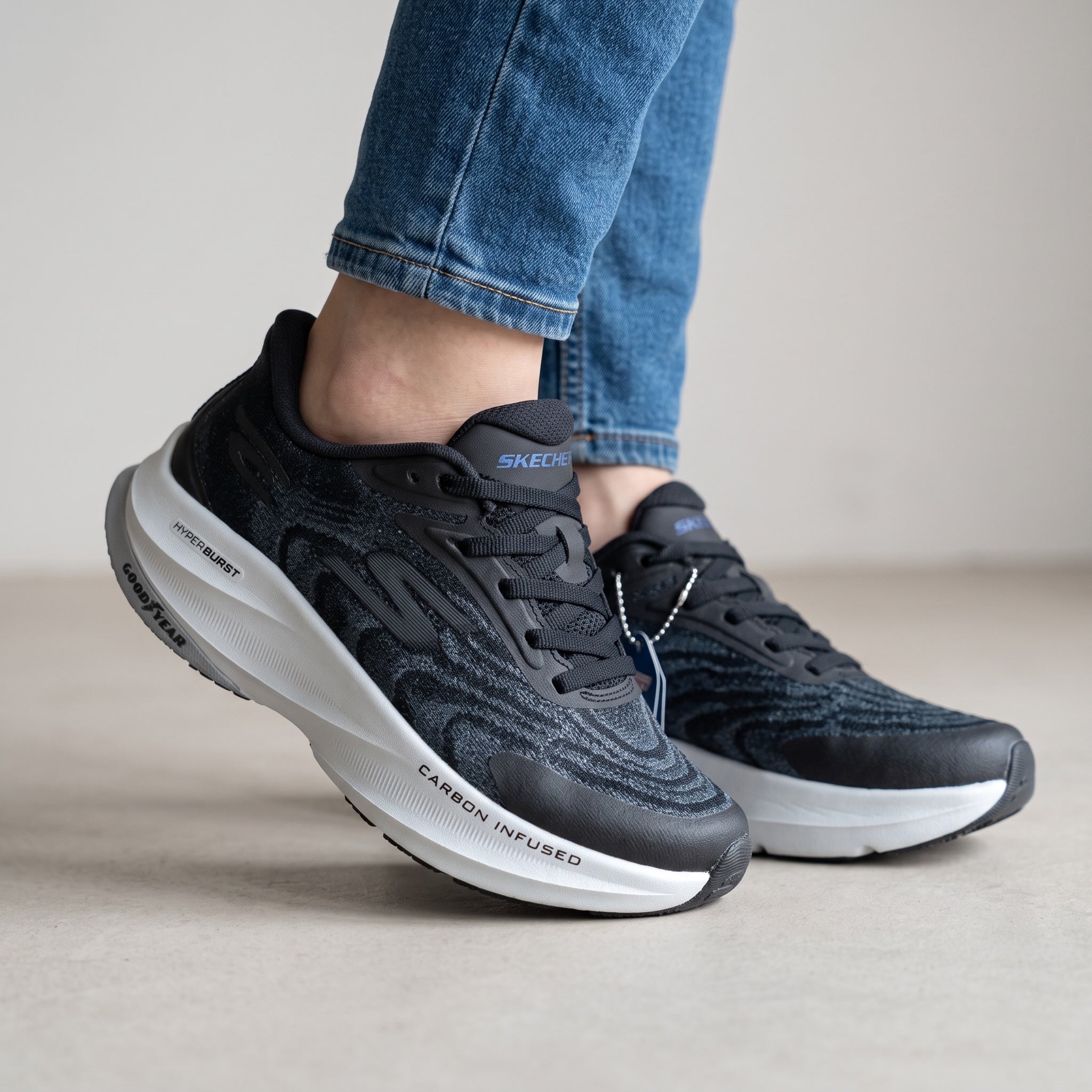 black Skechers knit running sneakers with white chunky midsole showing Carbon Infused and Hyperburst text