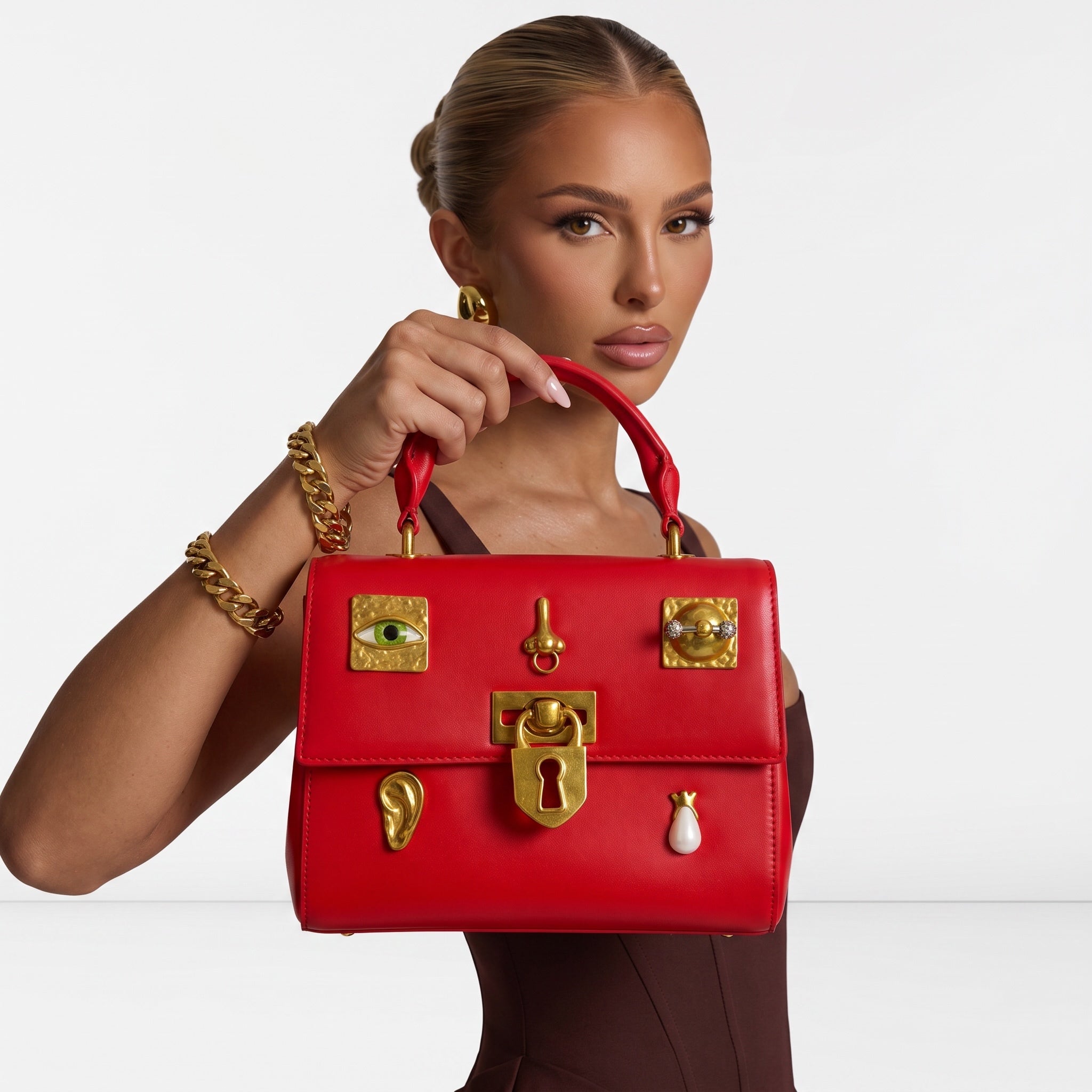 Red top-handle bag with gold-tone decorative charms and keyhole lock