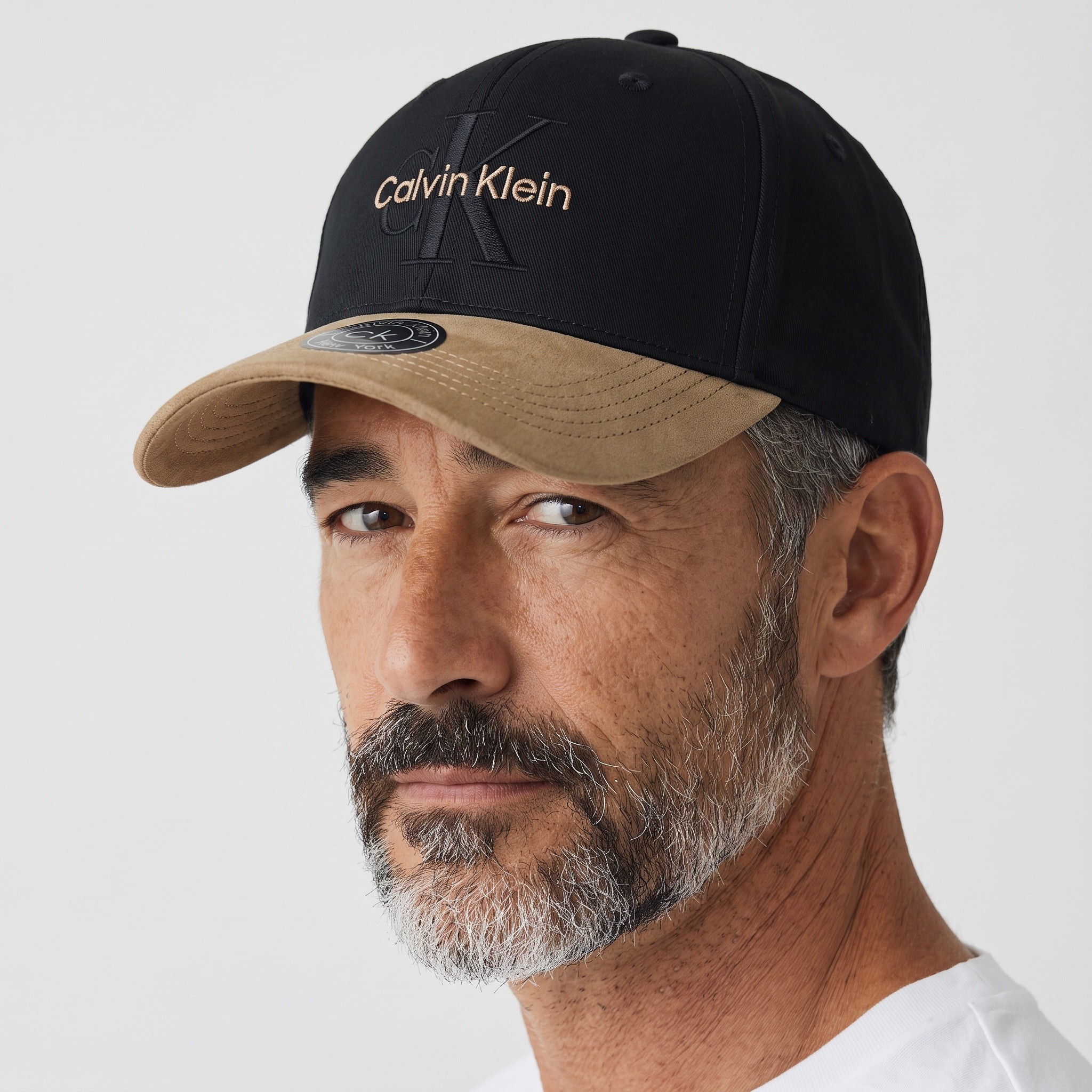 Man wearing a black and tan Calvin Klein baseball cap with embroidered CK logo