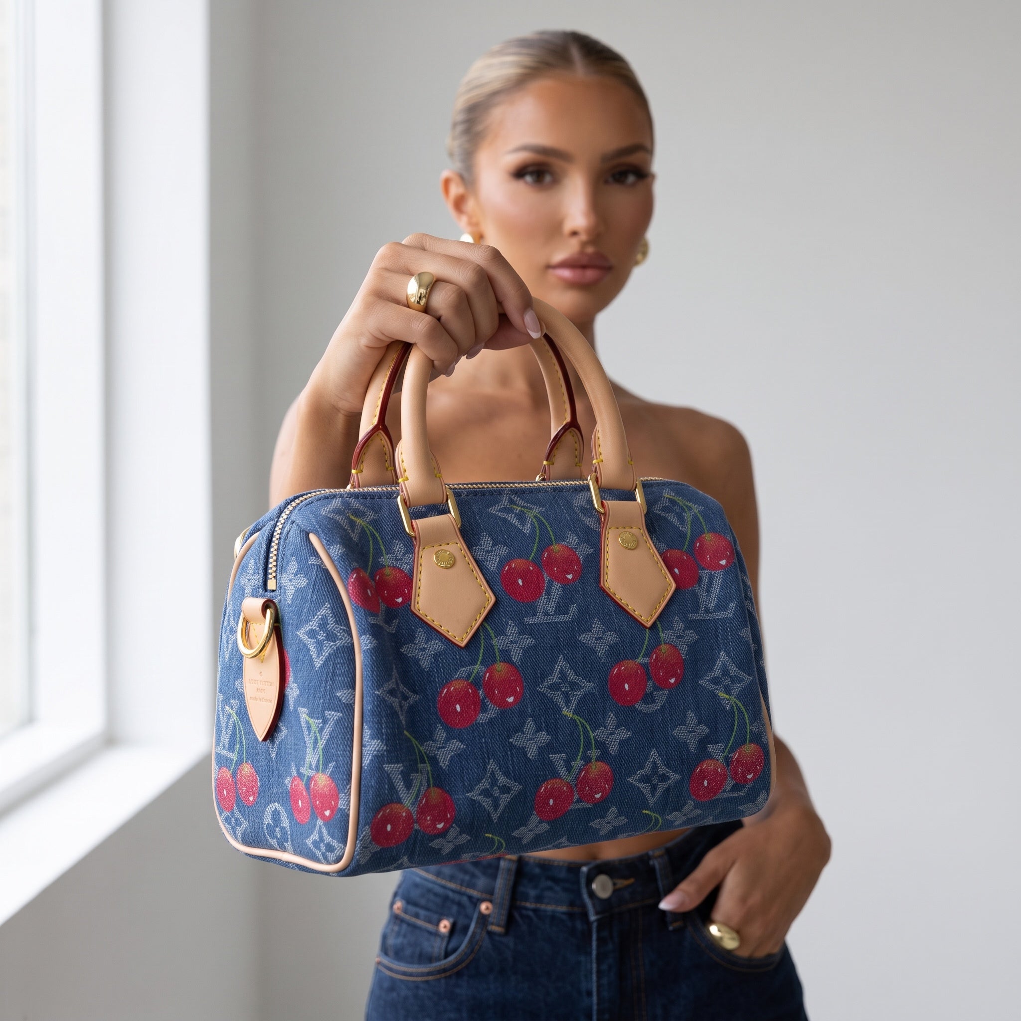 Blue denim Louis Vuitton cherry monogram handbag with leather handles held by model