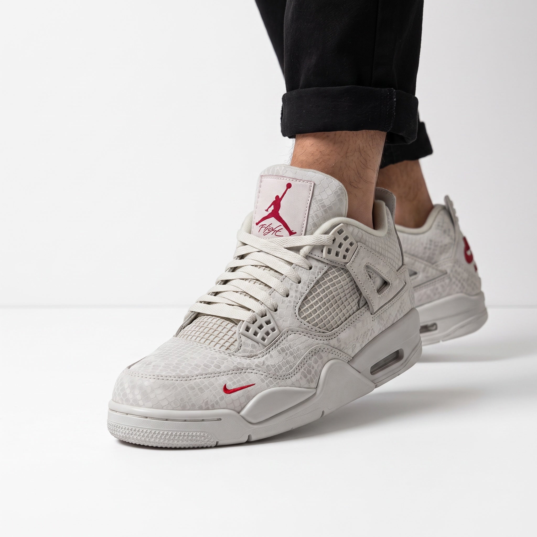 Light grey Jordan Air 4 sneakers with textured upper and red Jumpman logo