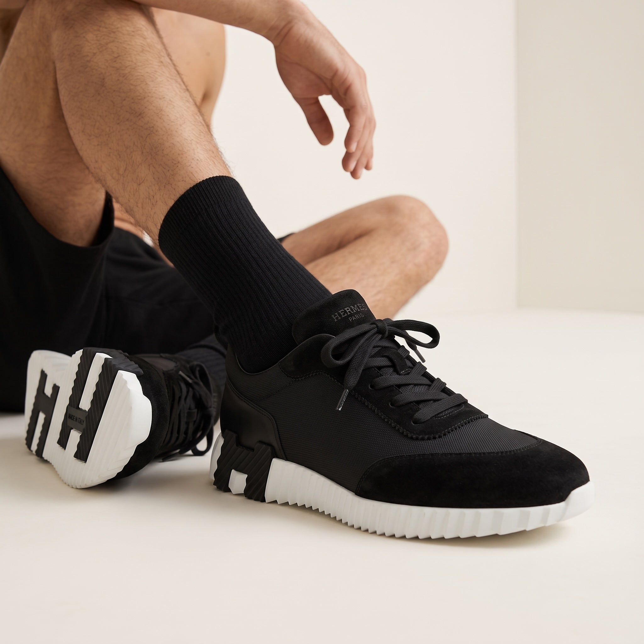 Hermès black low-top sneaker with white ridged sole and H-shaped black insert