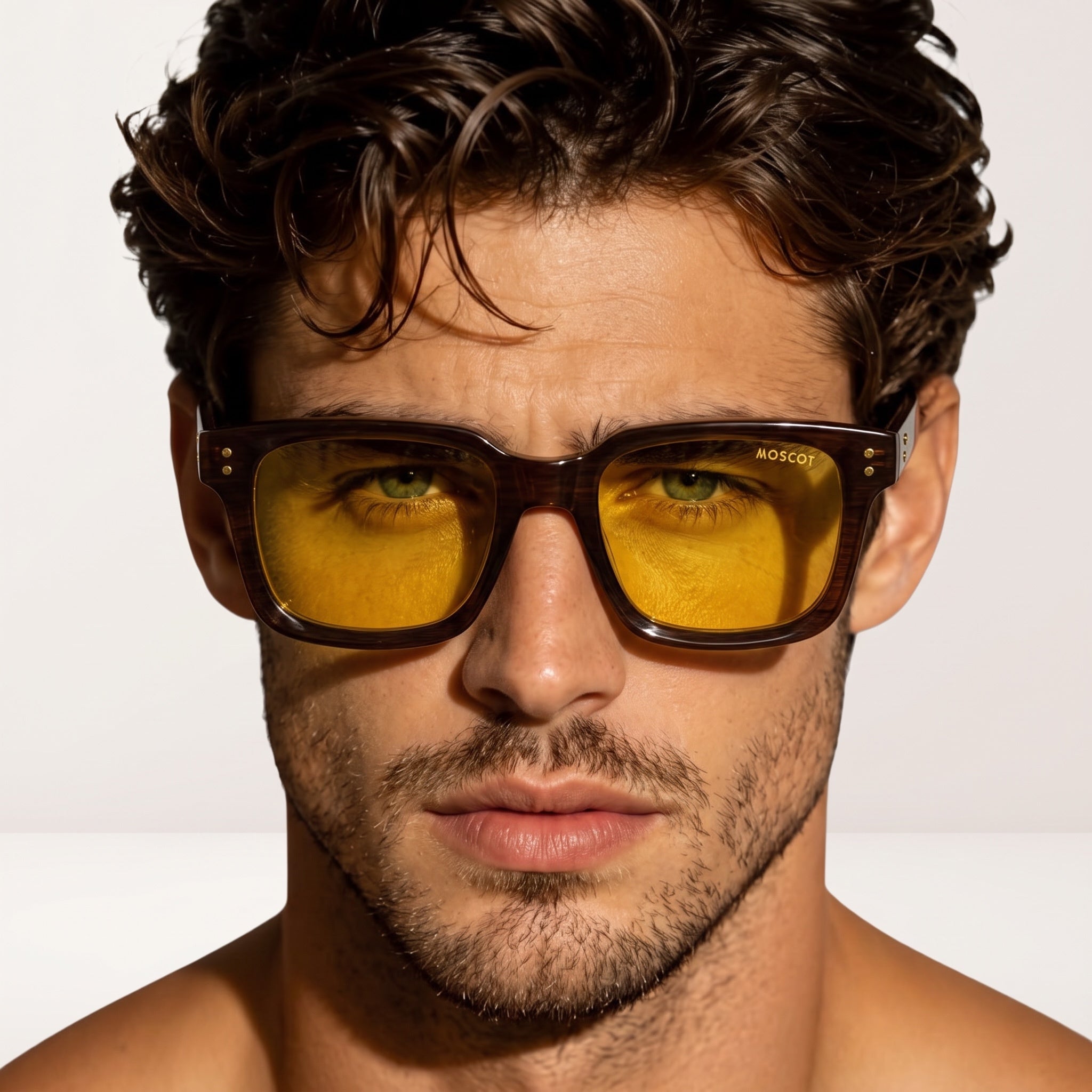 Close-up of Moscot tortoise sunglasses with amber lenses on male model.
