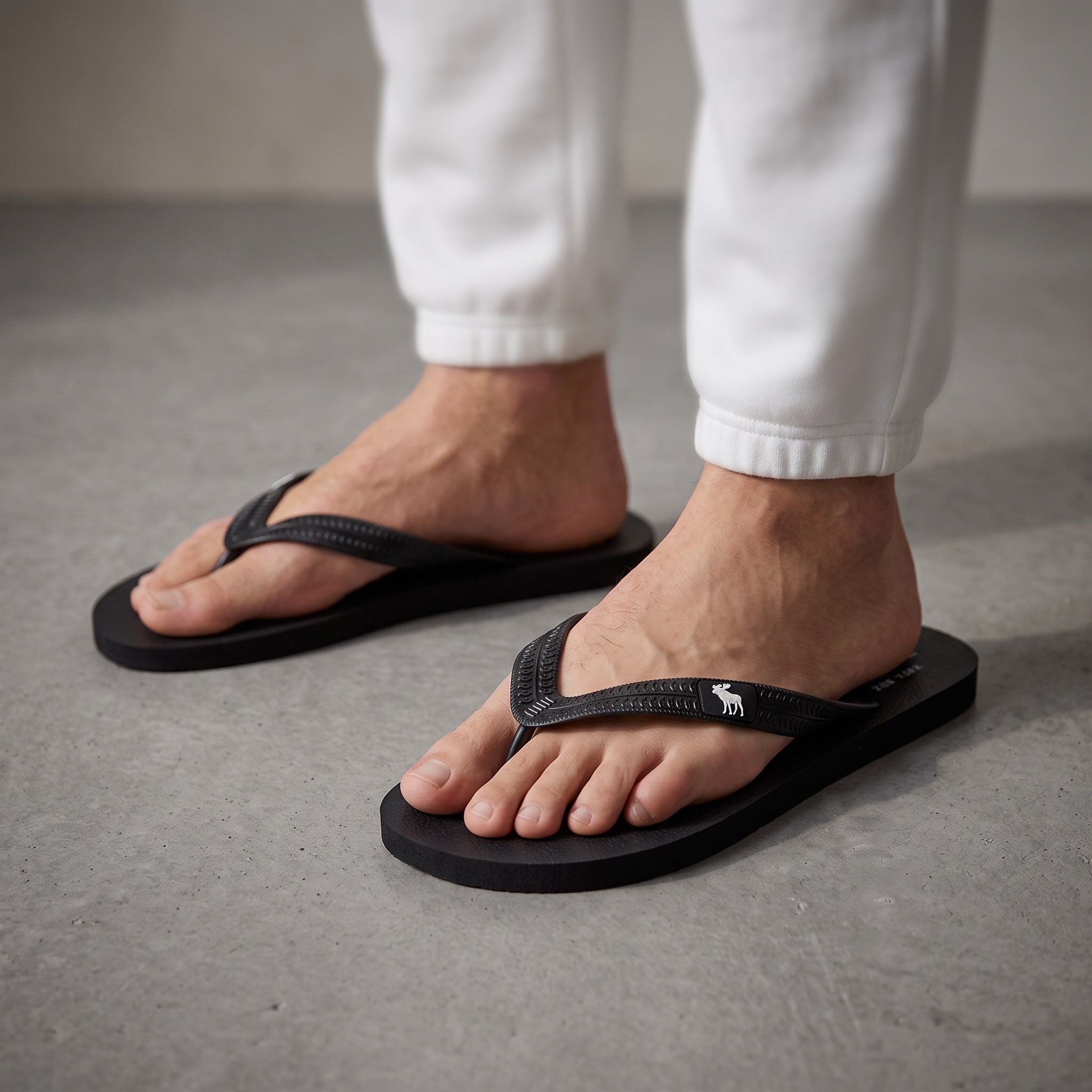 Close-up of black Abercrombie rubber flip flops with moose logo on strap