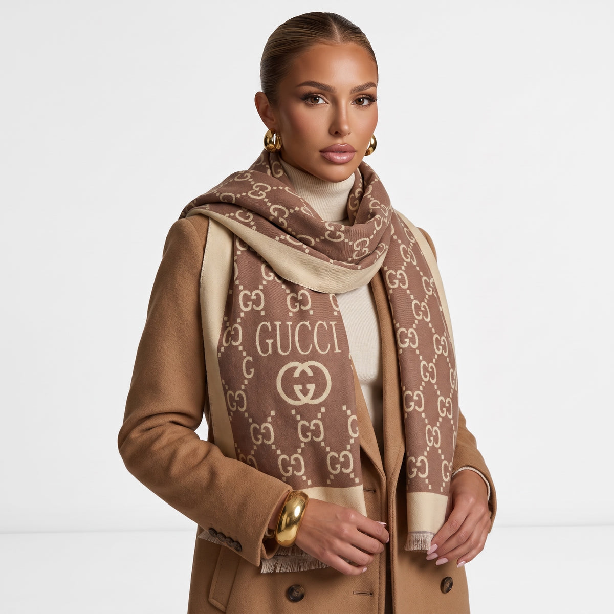 Brown Gucci monogram scarf draped over a camel coat showing GUCCI logo and fringed edge