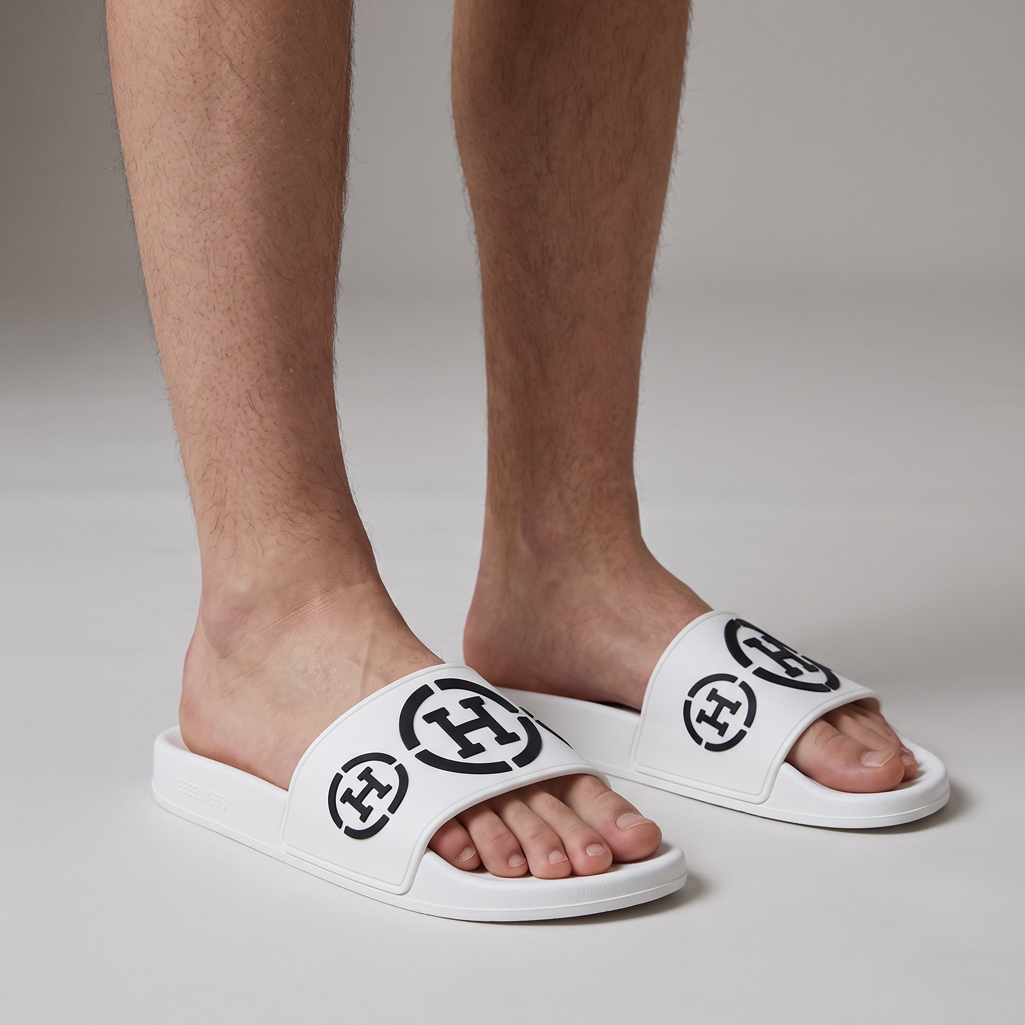 pair of white Gucci rubber logo slide sandals on model feet