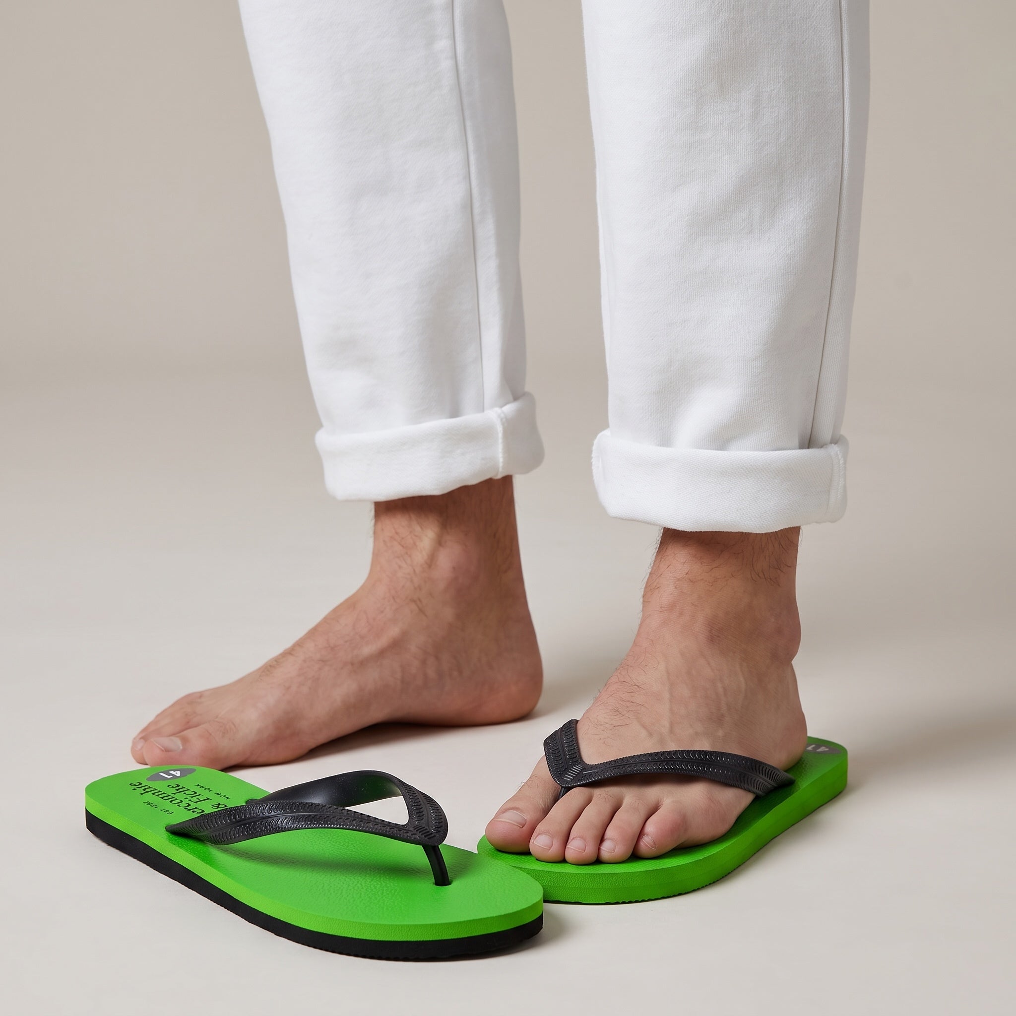 neon green Abercrombie & Fitch flip-flops with black straps on model feet
