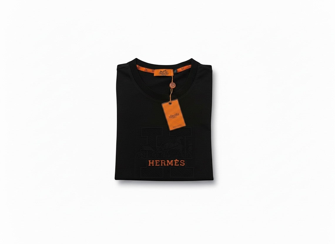 MASTERPIECE black cotton t-shirt with embossed orange Hermès H logo and signature orange tag detail.