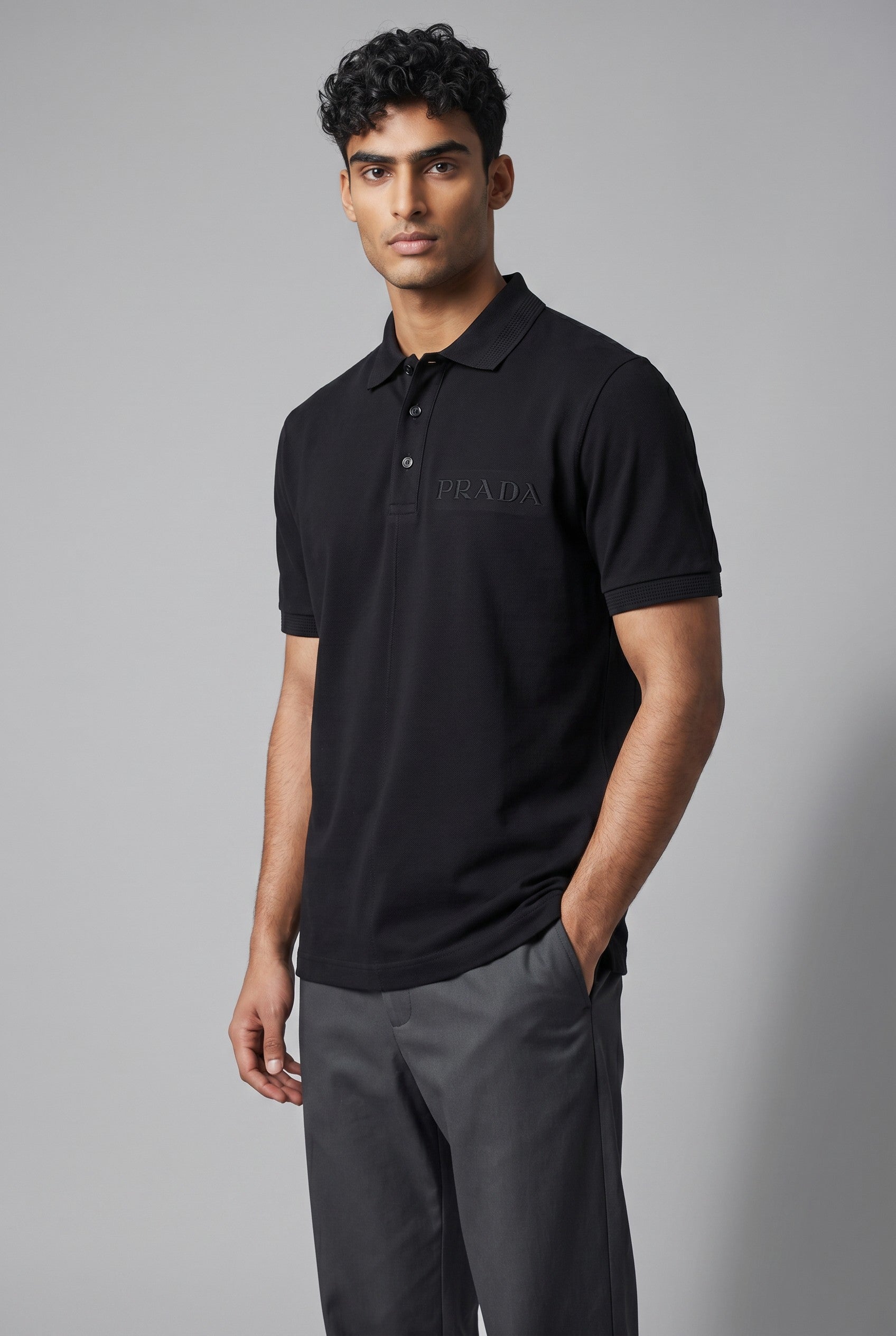 MASTERPIECE black stretch fabric polo shirt with tonal embossed Prada logo on chest, classic collar, and button placket.