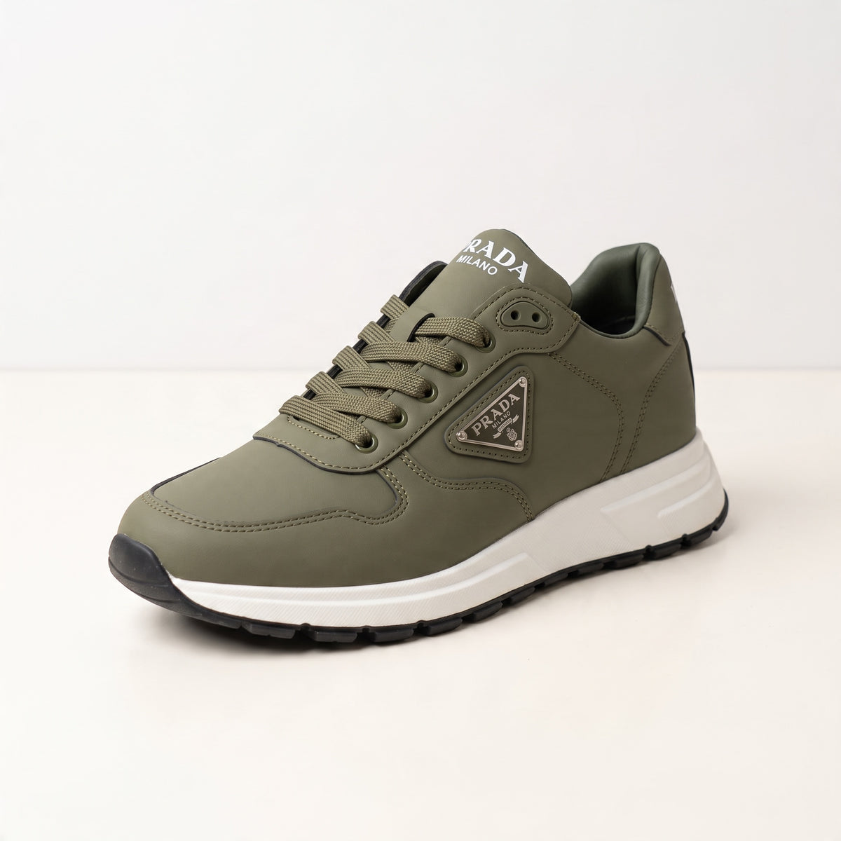 Olive green Prada low-top trainer with white chunky sole and triangular logo plaque