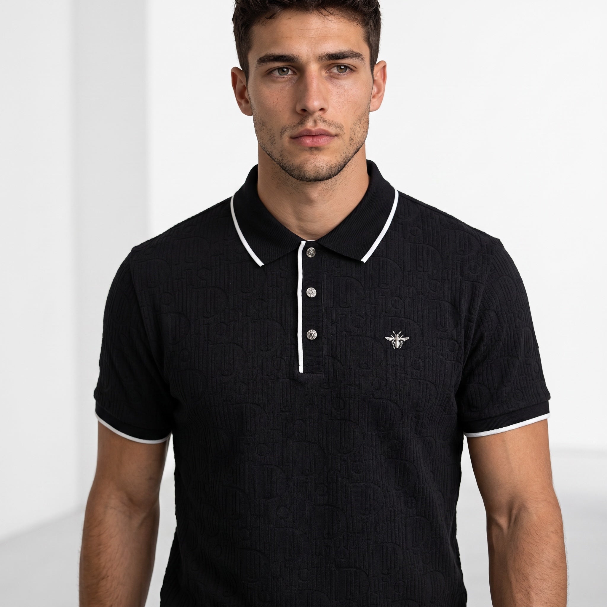 black short-sleeve polo with white piping, embossed logo pattern and metal bee emblem
